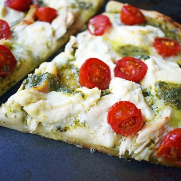 Chicken Pesto Pizza made with only 5 ingredients -- refrigerated pizza dough, pesto sauce, rotisserie chicken, ricotta cheese, and fresh mozzarella. May add grape tomatoes if so desired. An easy, flavorful homemade white pizza. www.modernhoney.com