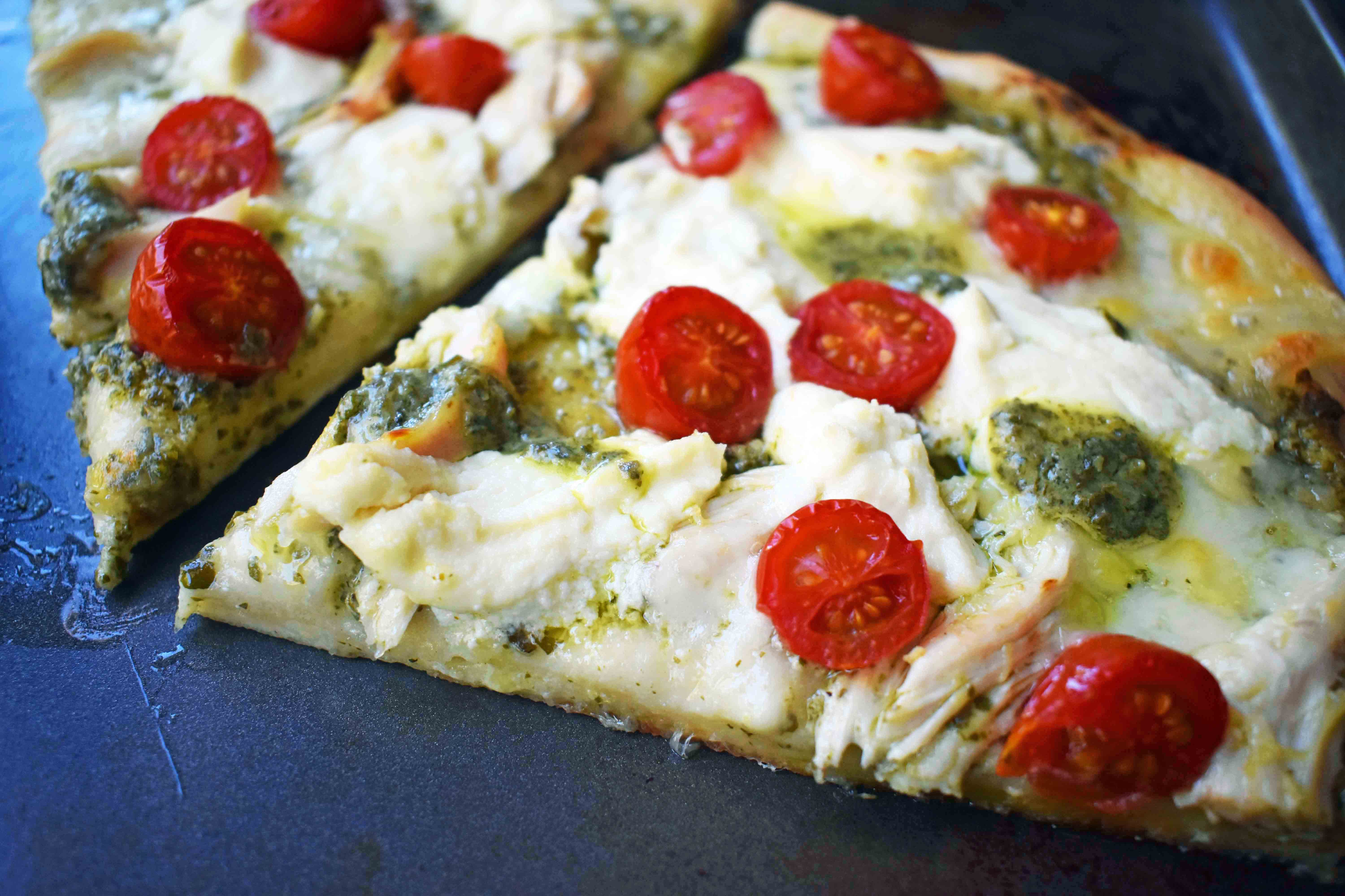 Chicken Pesto Pizza made with only 5 ingredients -- refrigerated pizza dough, pesto sauce, rotisserie chicken, ricotta cheese, and fresh mozzarella. May add grape tomatoes if so desired. An easy, flavorful homemade white pizza. www.modernhoney.com