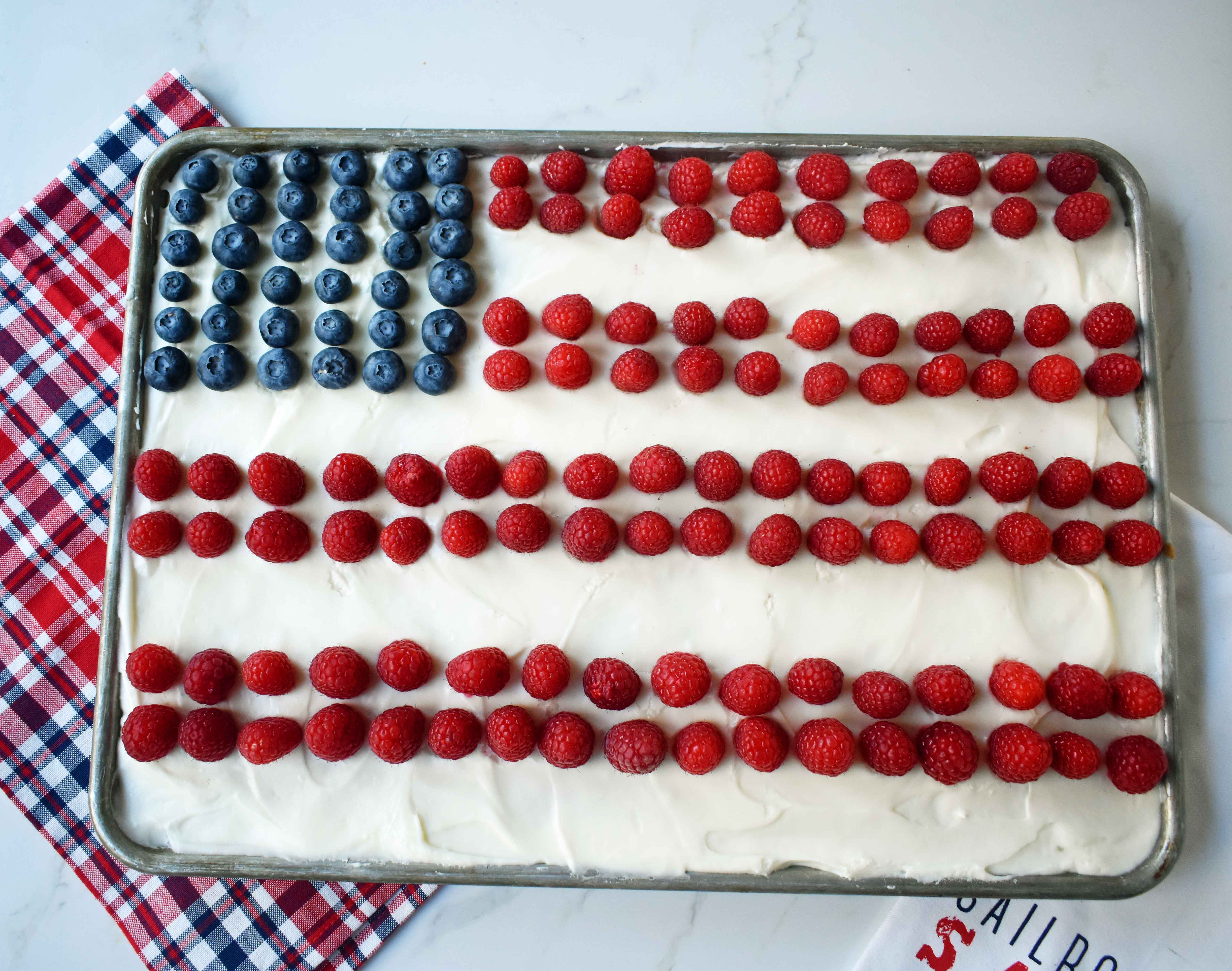 Vanilla Almond White Texas Sheet Cake. A vanilla white cake poured to a jelly roll pan and baked until moist and tender. Topped with almond cream cheese frosting and fresh berries. Perfect flag cake for a 4th of July celebration. www.modernhoney.com