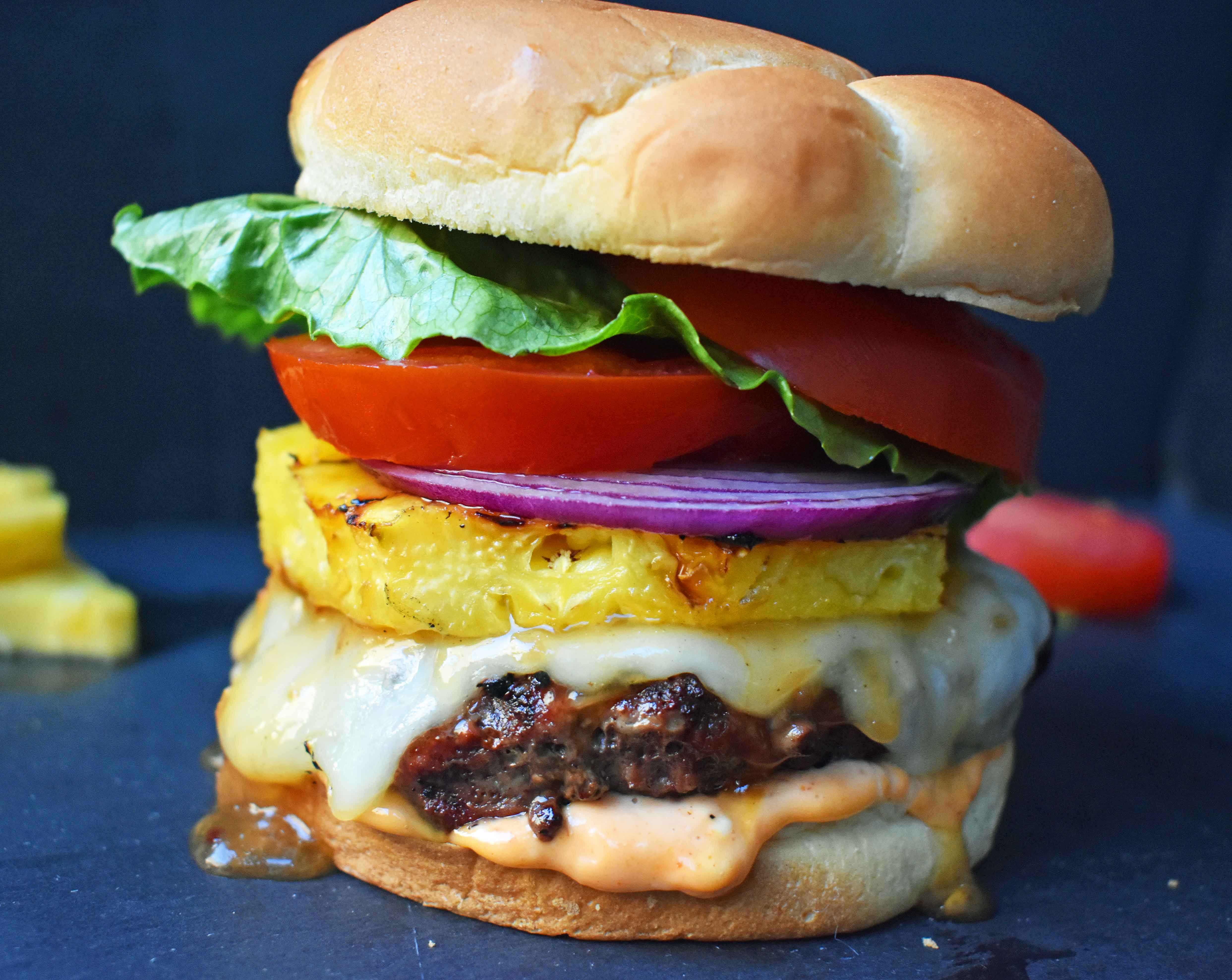 Sweet and Spicy Hawaiian Burger made with grass fed beef grilled to perfection and basted with a Hawaiian pineapple sauce and topped with melted Swiss Cheese. It is put on a warm toasted bun covered in Sriracha mayonnaise and topped with grilled pineapple, lettuce, tomato and red onion. A sweet and spicy burger that makes you think you are sitting on a beach in Hawaii! www.modernhoney.com