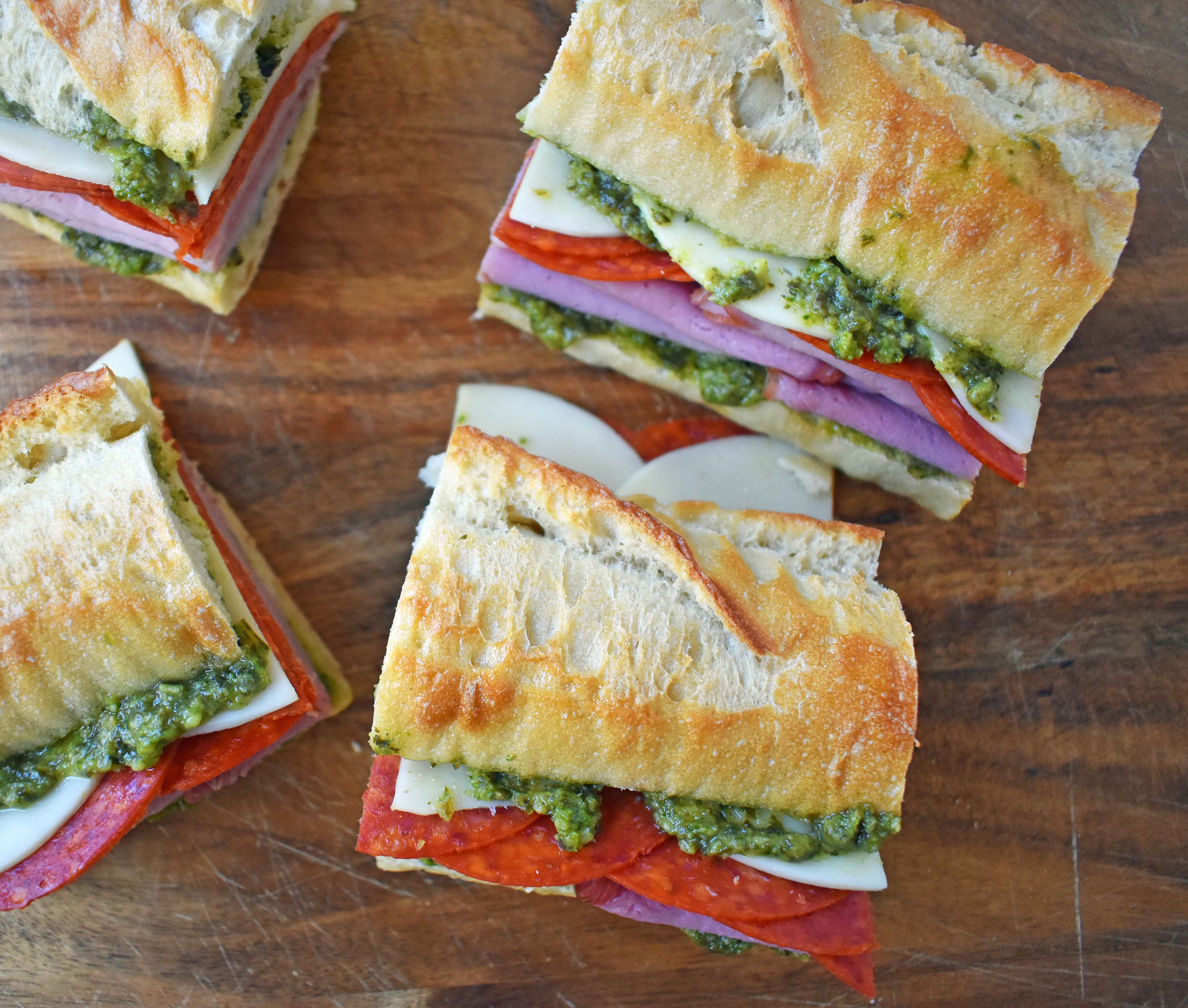 Italian Pressed Sandwiches made with rustic French bread layered with Italian meats and cheeses, pesto sauce or olive oil and vinegar, and marinated tomatoes. This Italian Pressed Sandwich with pesto sauce is perfect for a picnic, kids lunch, or for a casual lunch. www.modernhoney.com