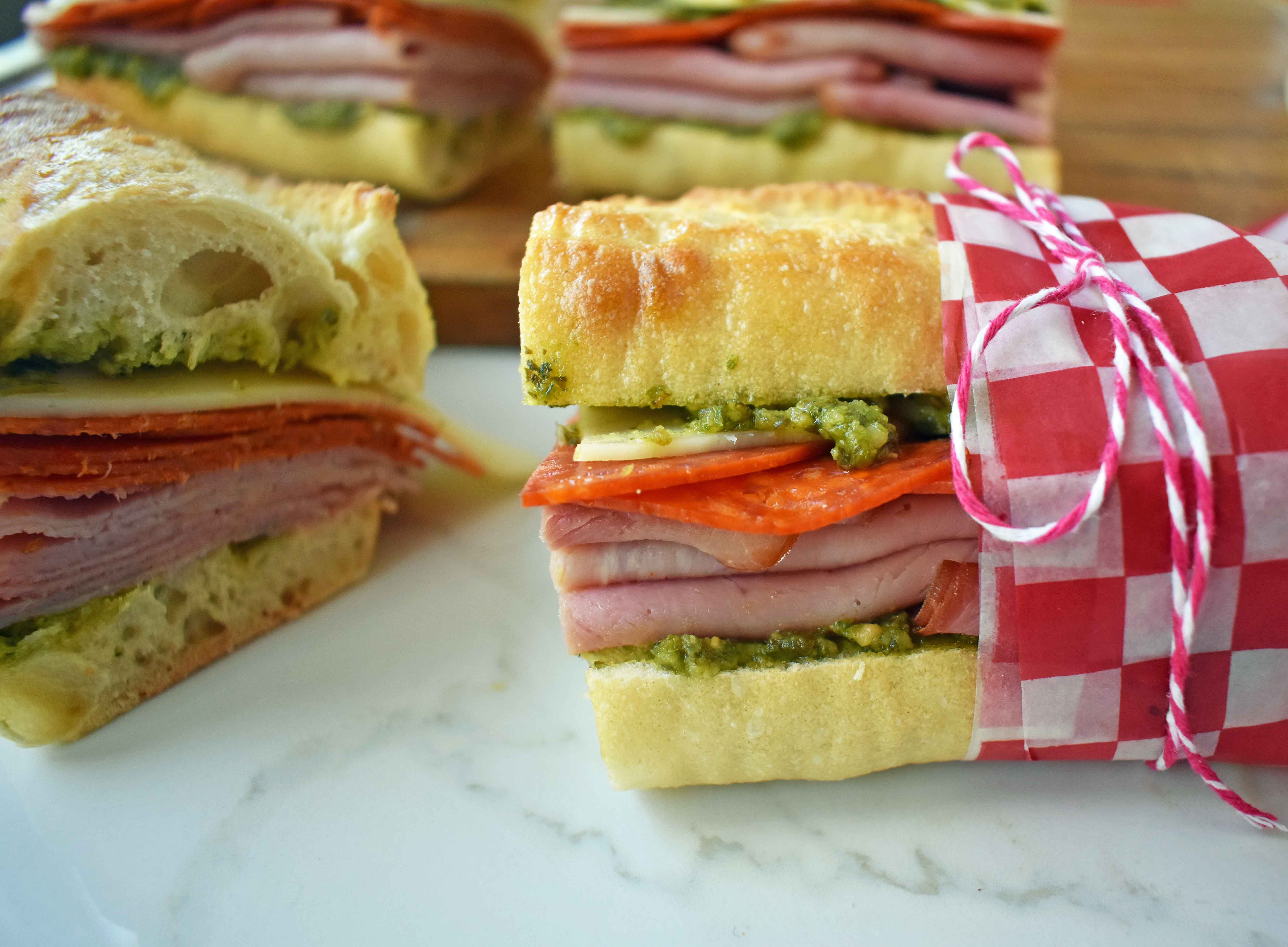 Italian Pressed Sandwiches made with rustic French bread layered with Italian meats and cheeses, pesto sauce or olive oil and vinegar, and marinated tomatoes. This Italian Pressed Sandwich with pesto sauce is perfect for a picnic, kids lunch, or for a casual lunch. www.modernhoney.com