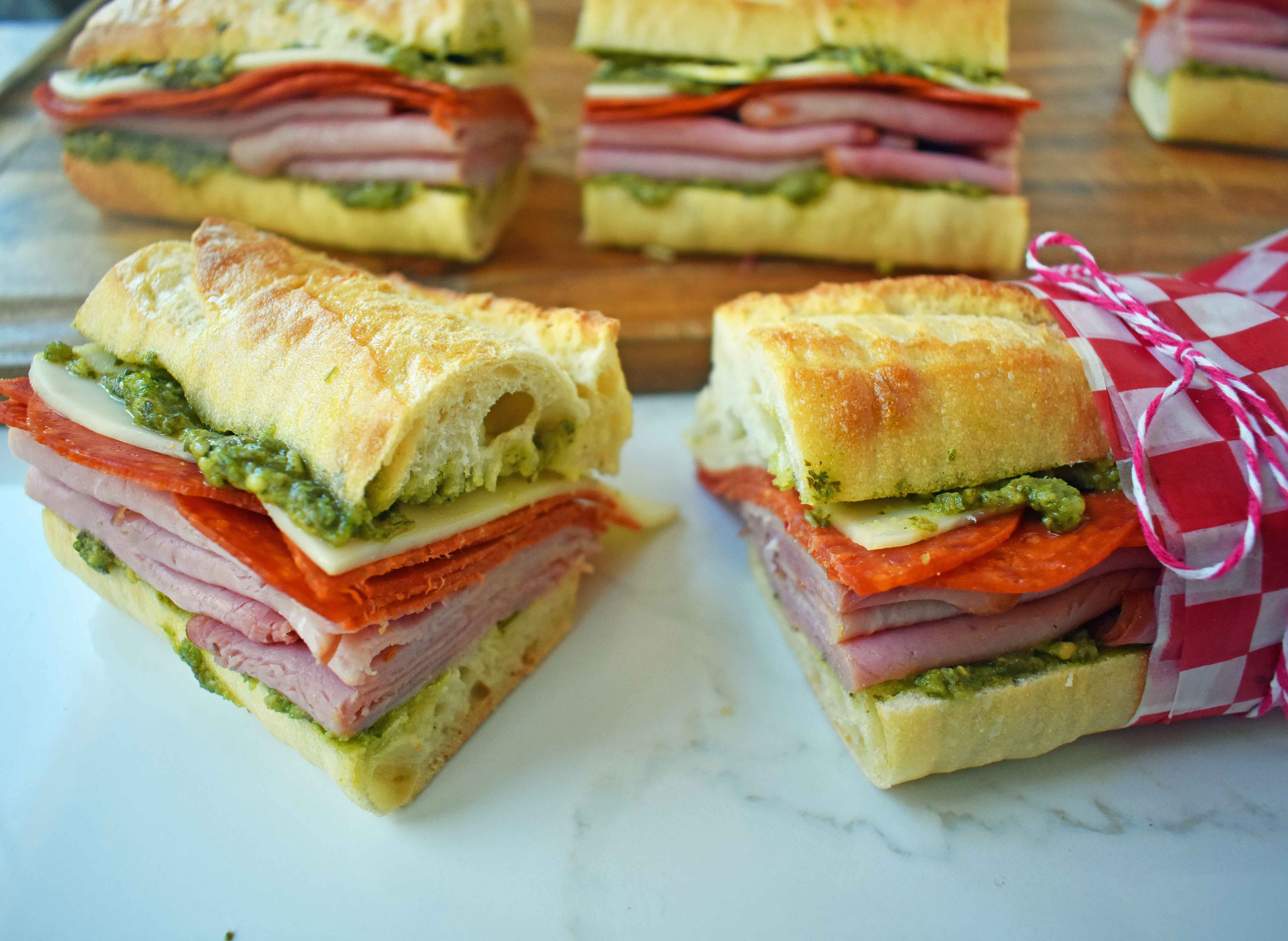 Italian Pressed Sandwiches made with rustic French bread layered with Italian meats and cheeses, pesto sauce or olive oil and vinegar, and marinated tomatoes. This Italian Pressed Sandwich with pesto sauce is perfect for a picnic, kids lunch, or for a casual lunch. www.modernhoney.com