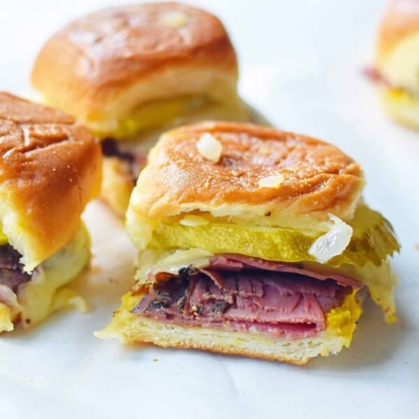 Hot Pastrami and Swiss Tailgate Sliders. Pastrami, creamy swiss, tangy mustard all on a hawaiian roll basted with garlic butter and baked until warm and toasty. A flavorful hot pastrami sandwich that is so easy! Perfect for entertaining, watching a football game, or a dinner at home. www.modernhoney.com