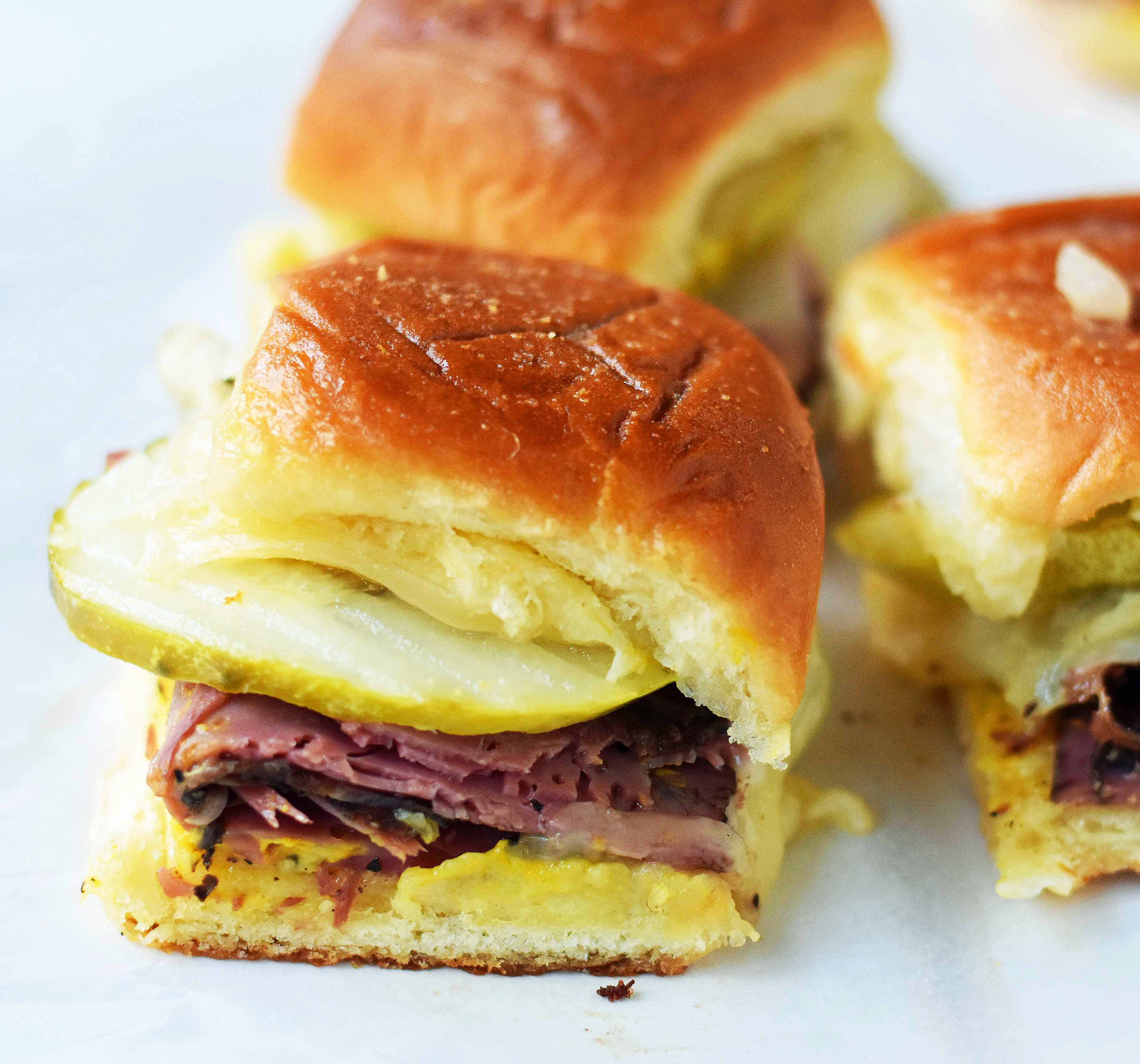 Hot Pastrami and Swiss Tailgate Sliders. Pastrami, creamy swiss, tangy mustard all on a hawaiian roll basted with garlic butter and baked until warm and toasty. A flavorful hot pastrami sandwich that is so easy! Perfect for entertaining, watching a football game, or a dinner at home. www.modernhoney.com