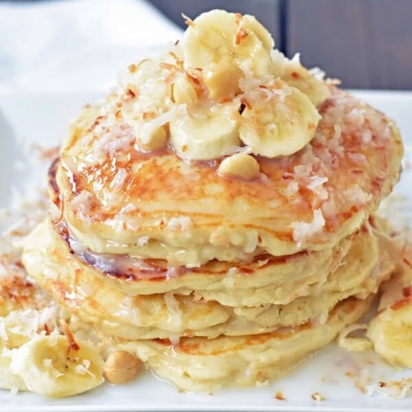 Toasted Coconut Macadamia Pancakes with Coconut Syrup are the most perfect tropical pancakes. Light and fluffy toasted coconut pancakes topped with homemade coconut syrup and macadamia nuts. www.modernhoney.com
