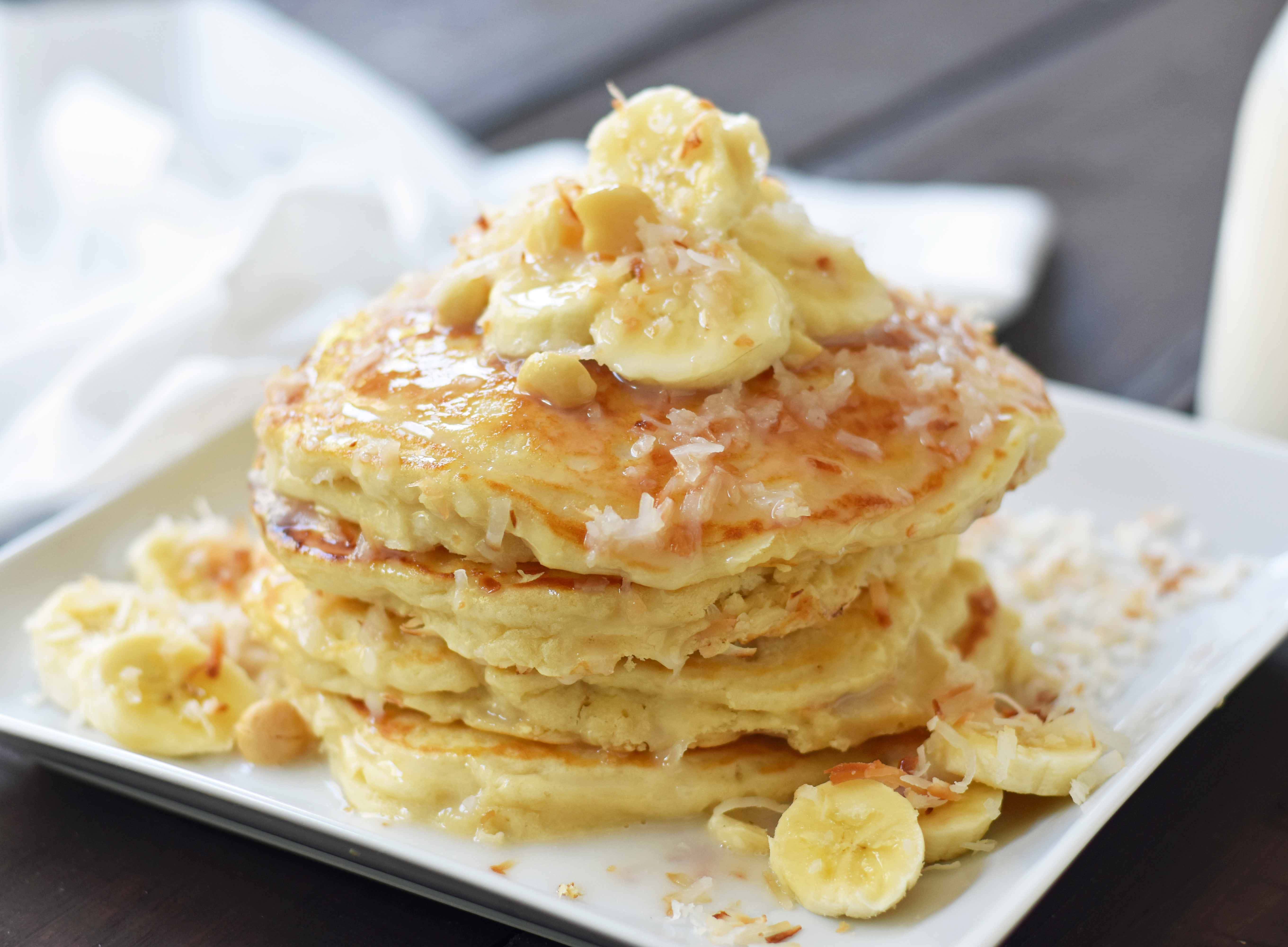 Toasted Coconut Macadamia Pancakes with Coconut Syrup are the most perfect tropical pancakes. Light and fluffy toasted coconut pancakes topped with homemade coconut syrup and macadamia nuts. www.modernhoney.com