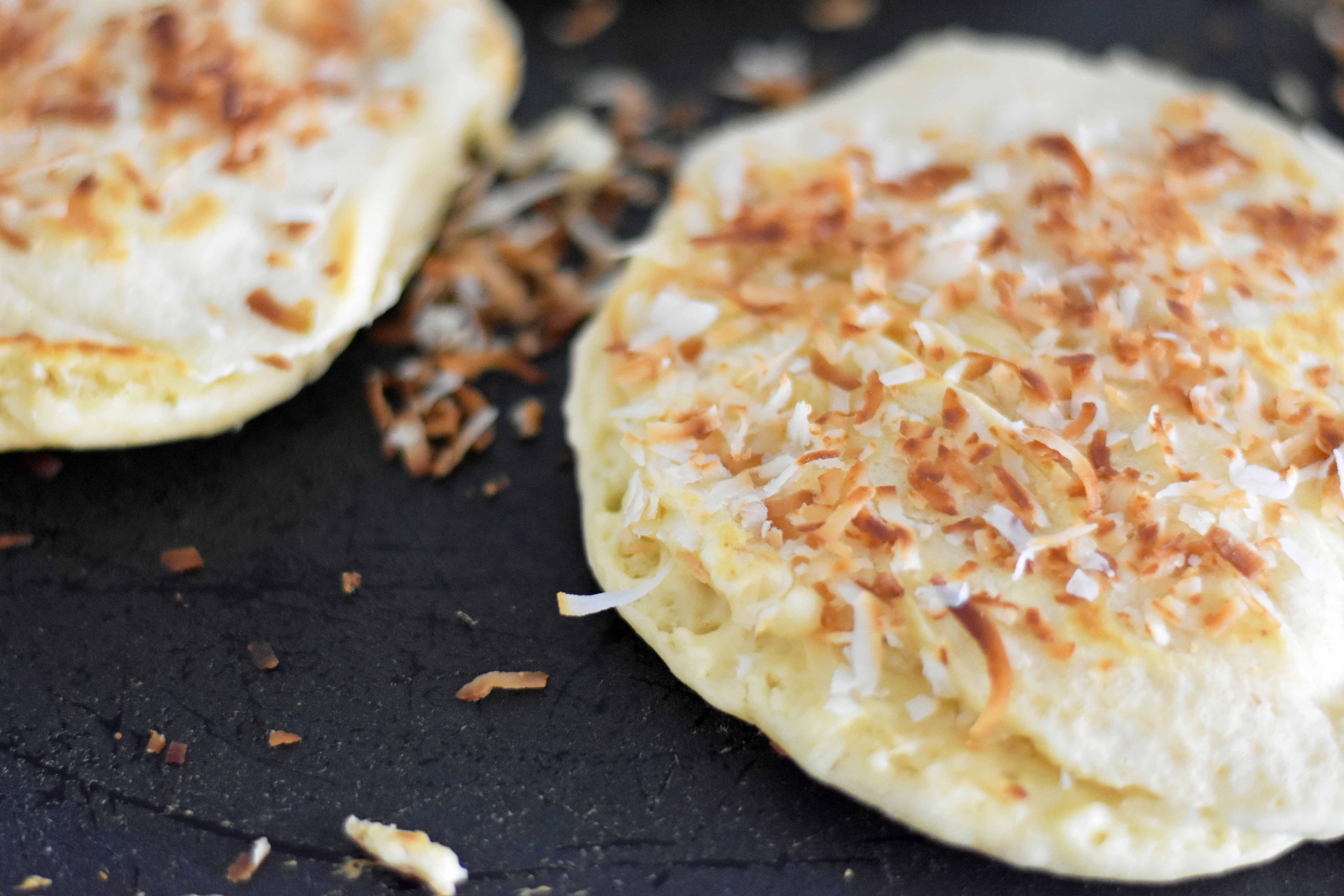 Toasted Coconut Macadamia Pancakes with Coconut Syrup are the most perfect tropical pancakes. Light and fluffy toasted coconut pancakes topped with homemade coconut syrup and macadamia nuts. www.modernhoney.com