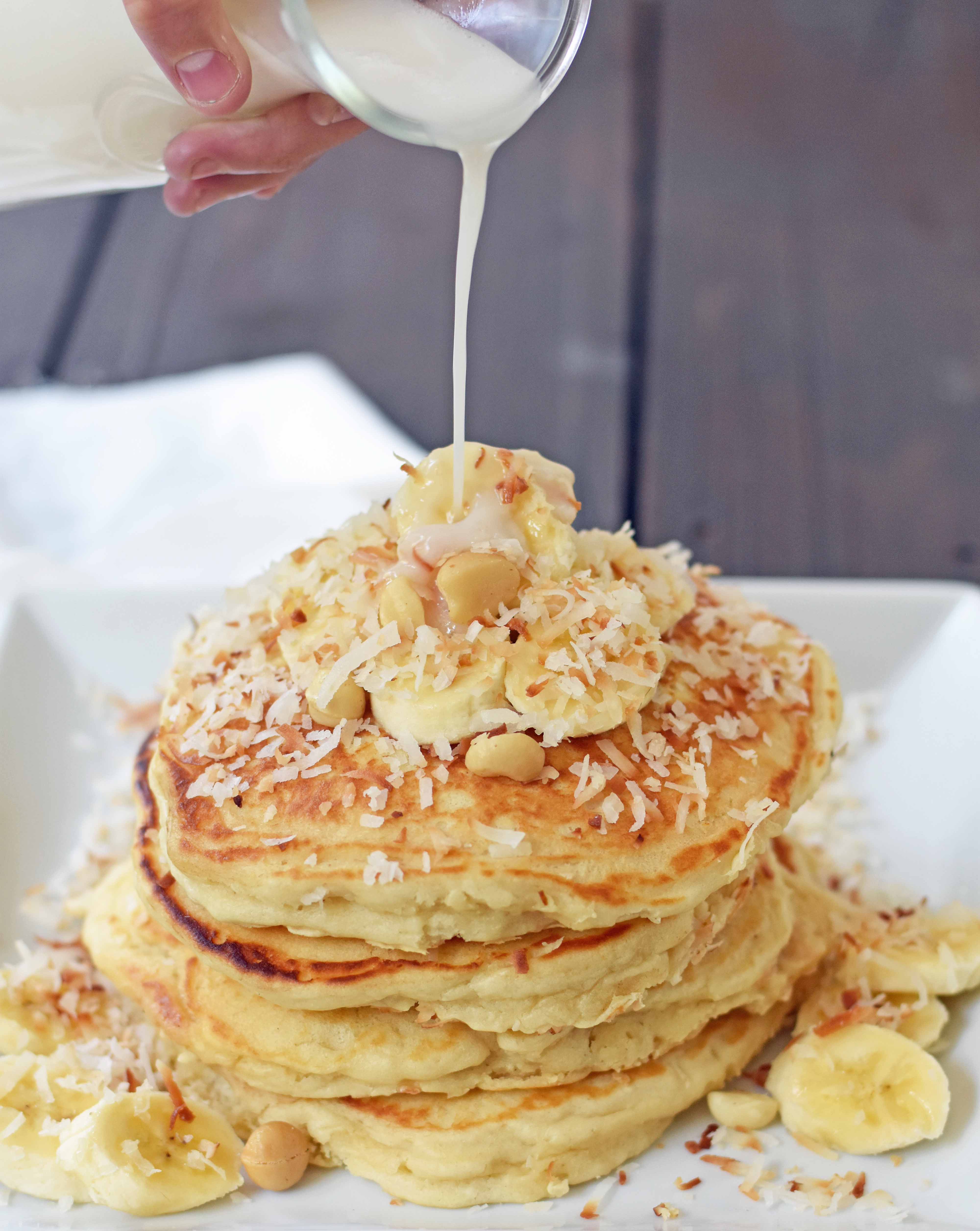 Toasted Coconut Macadamia Pancakes with Coconut Syrup are the most perfect tropical pancakes. Light and fluffy toasted coconut pancakes topped with homemade coconut syrup and macadamia nuts. www.modernhoney.com