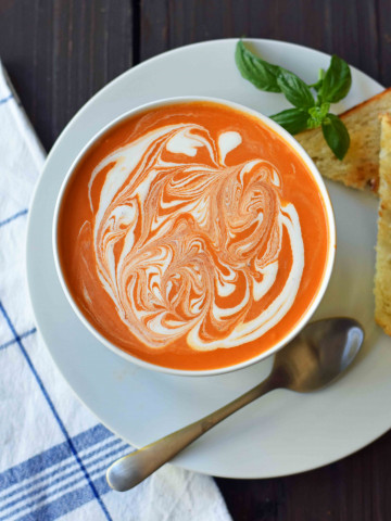 Creamy Tomato Basil Soup is the best cream of tomato soup. This Creamy Tomato Basil Soup Recipe using sauteed onions, garlic, tomatoes, chicken broth, basil, and heavy cream. You will never eat canned tomato soup again! The best creamy tomato soup recipe. www.modernhoney.com