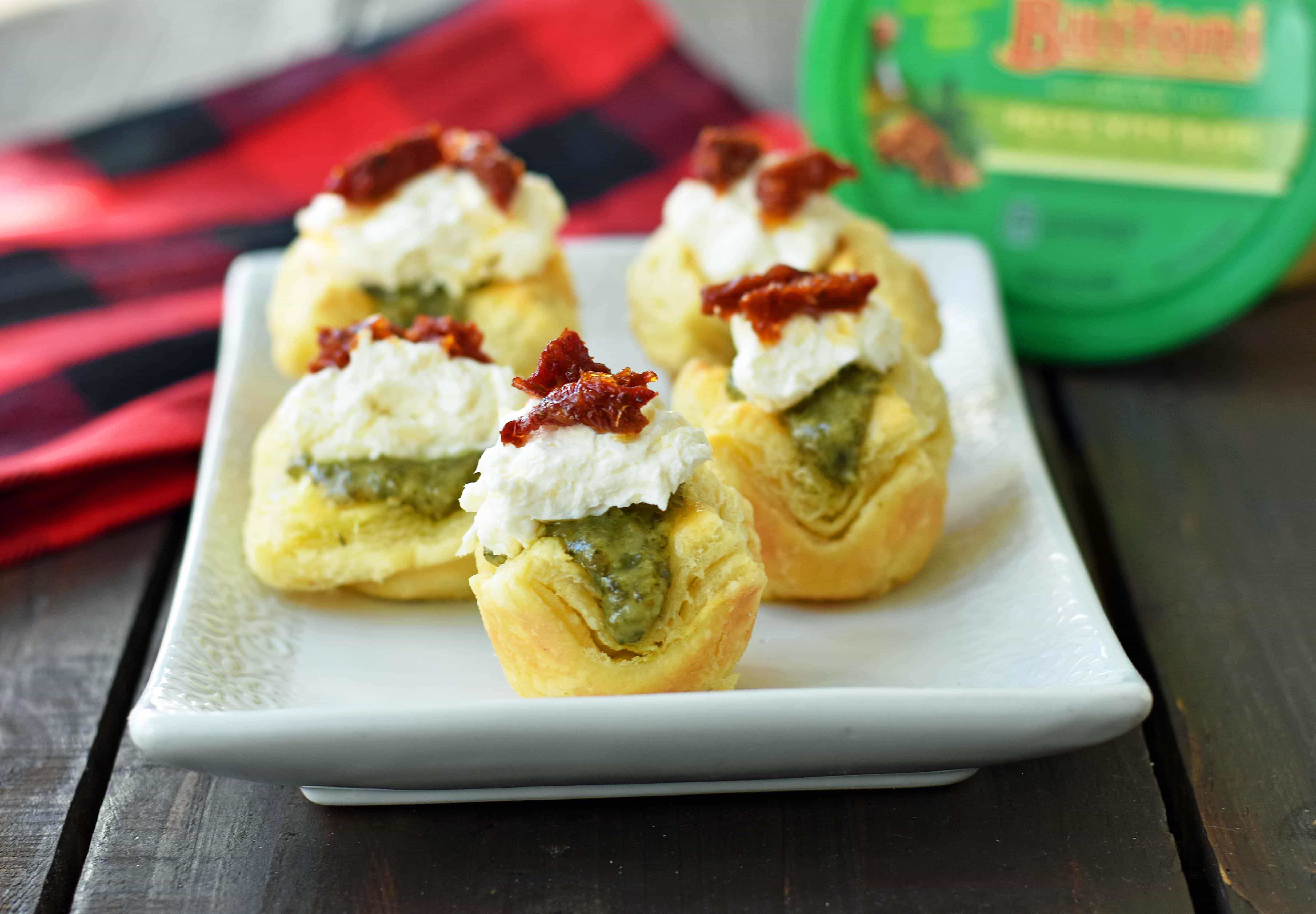 Pesto Parmesan Sundried Tomato Tartlets are made with flaky puff pastry baked until golden brown and filled with Buitoni freshly made pesto sauce, a parmesan goat cheese cream cheese layer, and topped with sweet sundried tomatoes. A beautiful and festive holiday appetizer. www.modernhoney.com @buitoniusa #sponsored 