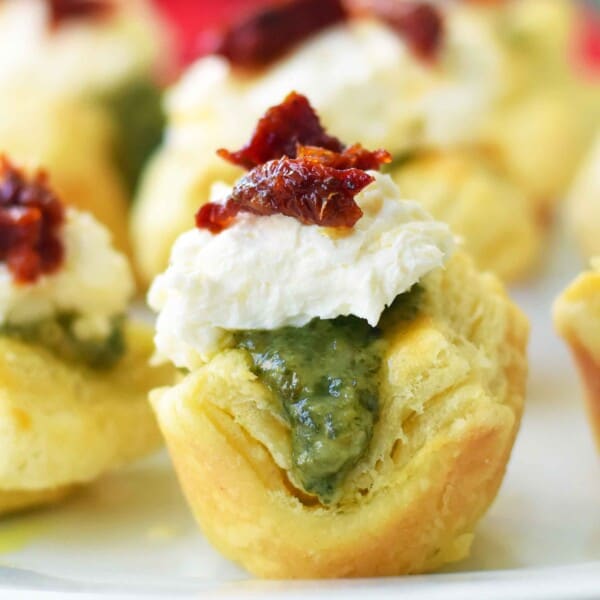 Pesto Parmesan Sundried Tomato Tartlets are made with flaky puff pastry baked until golden brown and filled with Buitoni freshly made pesto sauce, a parmesan goat cheese cream cheese layer, and topped with sweet sundried tomatoes. A beautiful and festive holiday appetizer. www.modernhoney.com @buitoniusa #sponsored