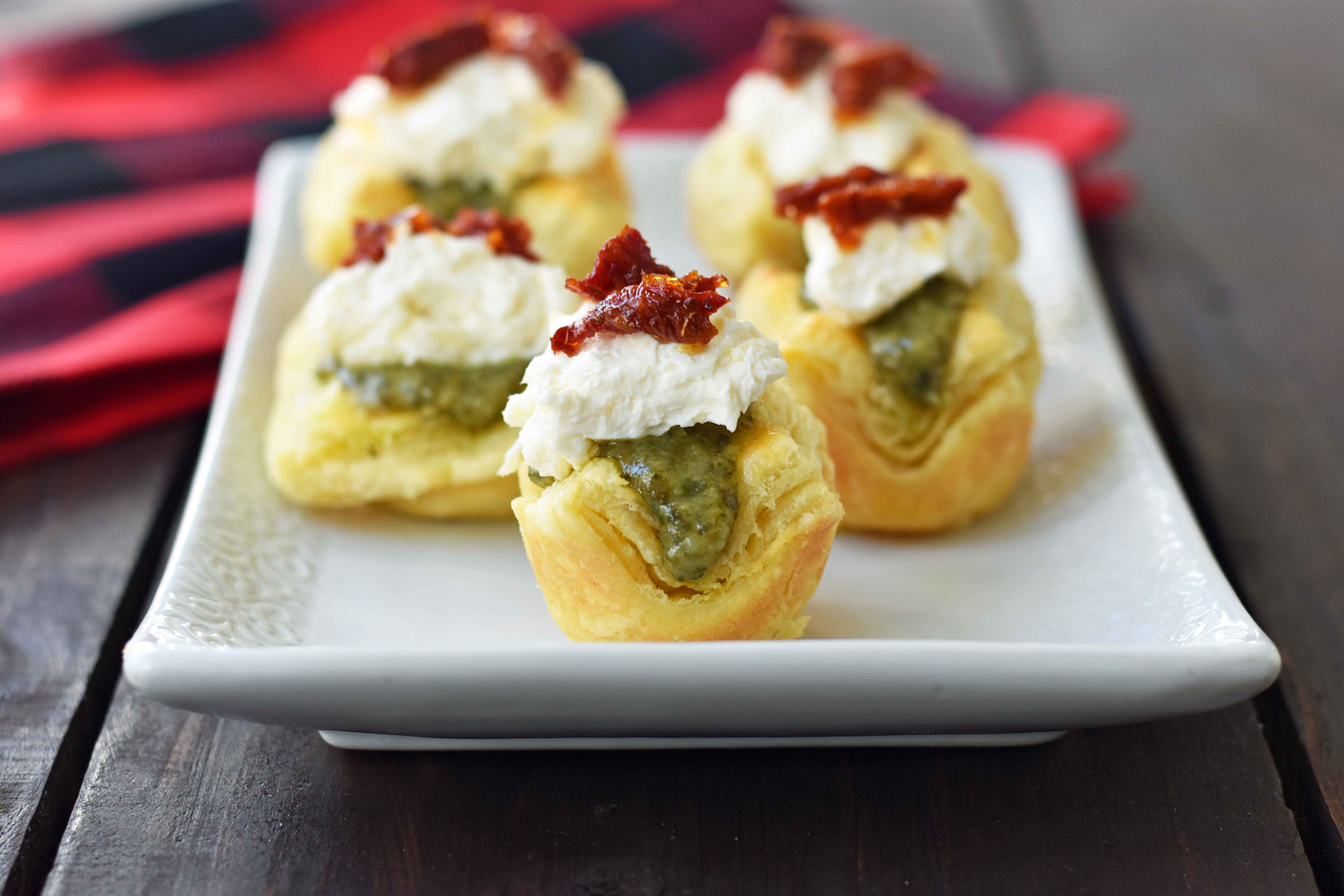 Pesto Parmesan Sundried Tomato Tartlets are made with flaky puff pastry baked until golden brown and filled with Buitoni freshly made pesto sauce, a parmesan goat cheese cream cheese layer, and topped with sweet sundried tomatoes. A beautiful and festive holiday appetizer. www.modernhoney.com @buitoniusa #sponsored 