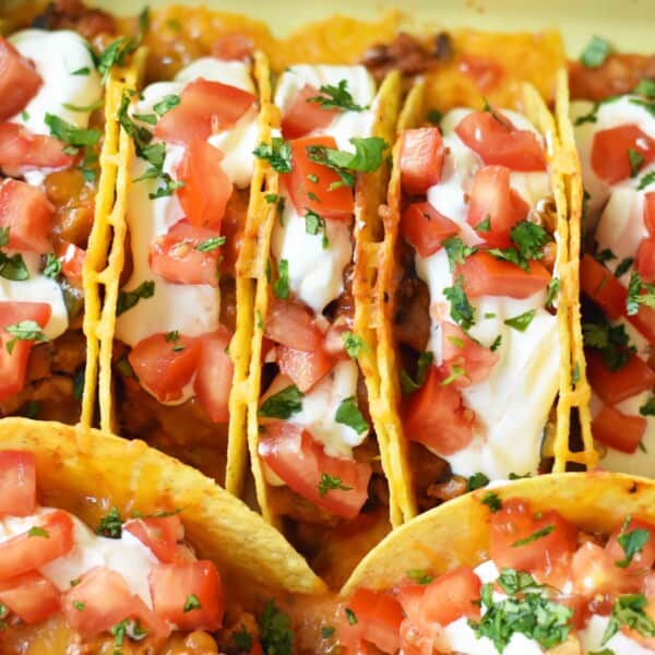 Easy Oven Baked Beef Tacos. Perfectly seasoned ground beef tacos and Mexican cheese baked in taco shells until melted. Topped with sour cream, guacamole, salsa, diced tomatoes, and hot sauce. These are party tacos and a family favorite dinner. www.modernhoney.com