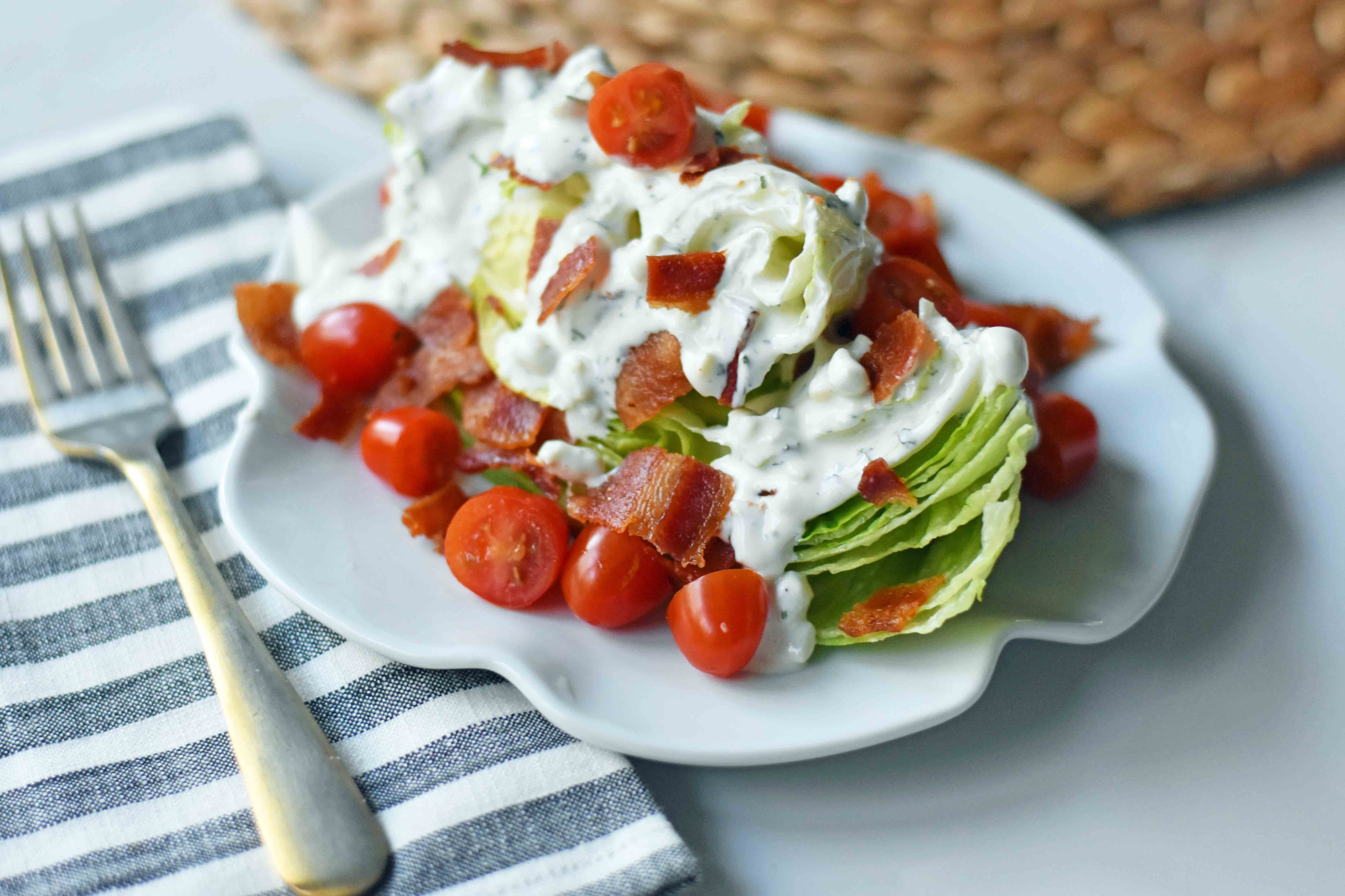 Ultimate Wedge Salad made with crisp iceberg lettuce, fresh cherry tomatoes, crispy bacon, with a homemade creamy ranch or blue cheese dressing. A classic, crowd-favorite salad. www.modernhoney.com