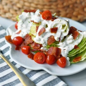 Ultimate Wedge Salad made with crisp iceberg lettuce, fresh cherry tomatoes, crispy bacon, with a homemade creamy ranch or blue cheese dressing. A classic, crowd-favorite salad. www.modernhoney.com