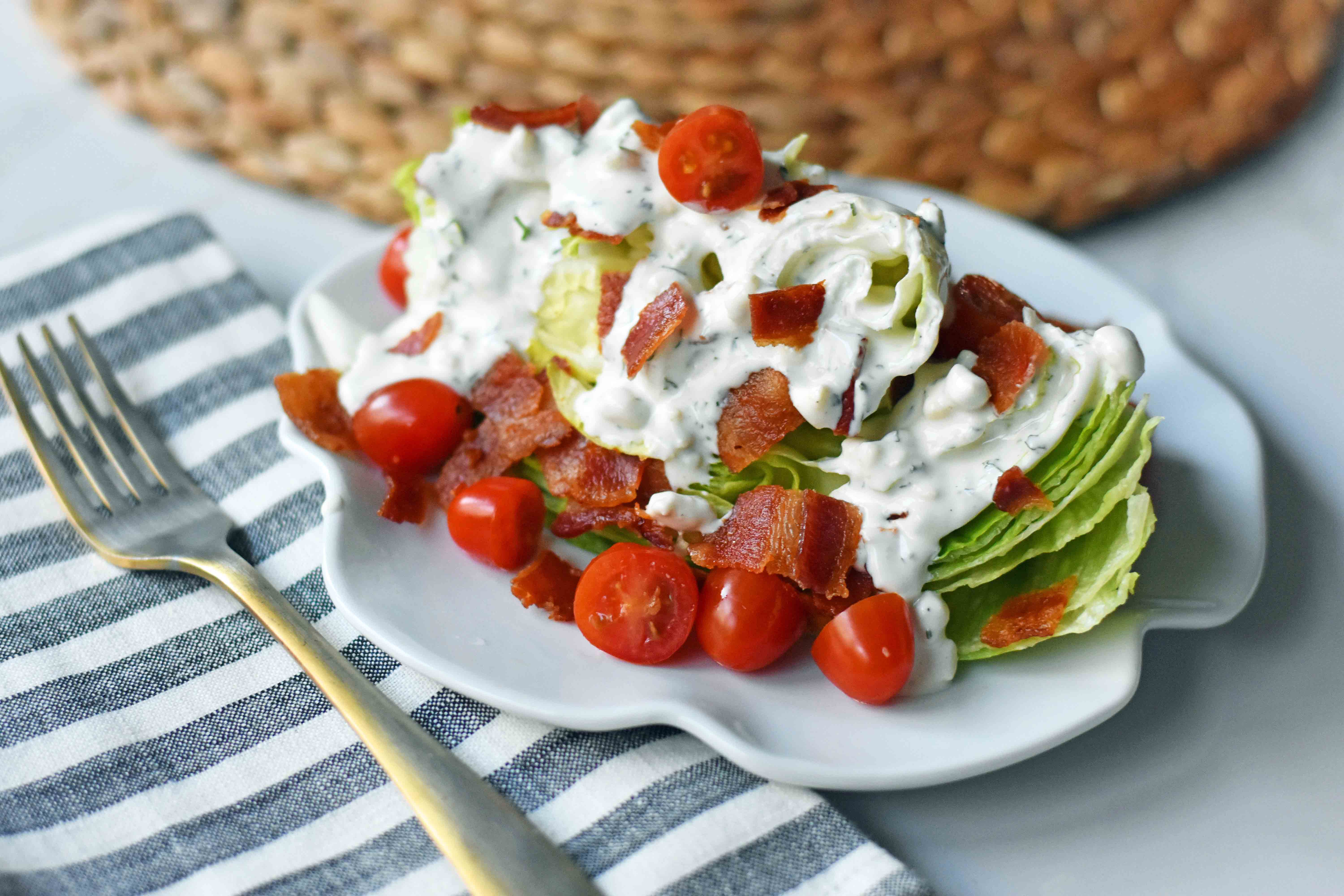 Ultimate Wedge Salad made with crisp iceberg lettuce, fresh cherry tomatoes, crispy bacon, with a homemade creamy ranch or blue cheese dressing. A classic, crowd-favorite salad. www.modernhoney.com