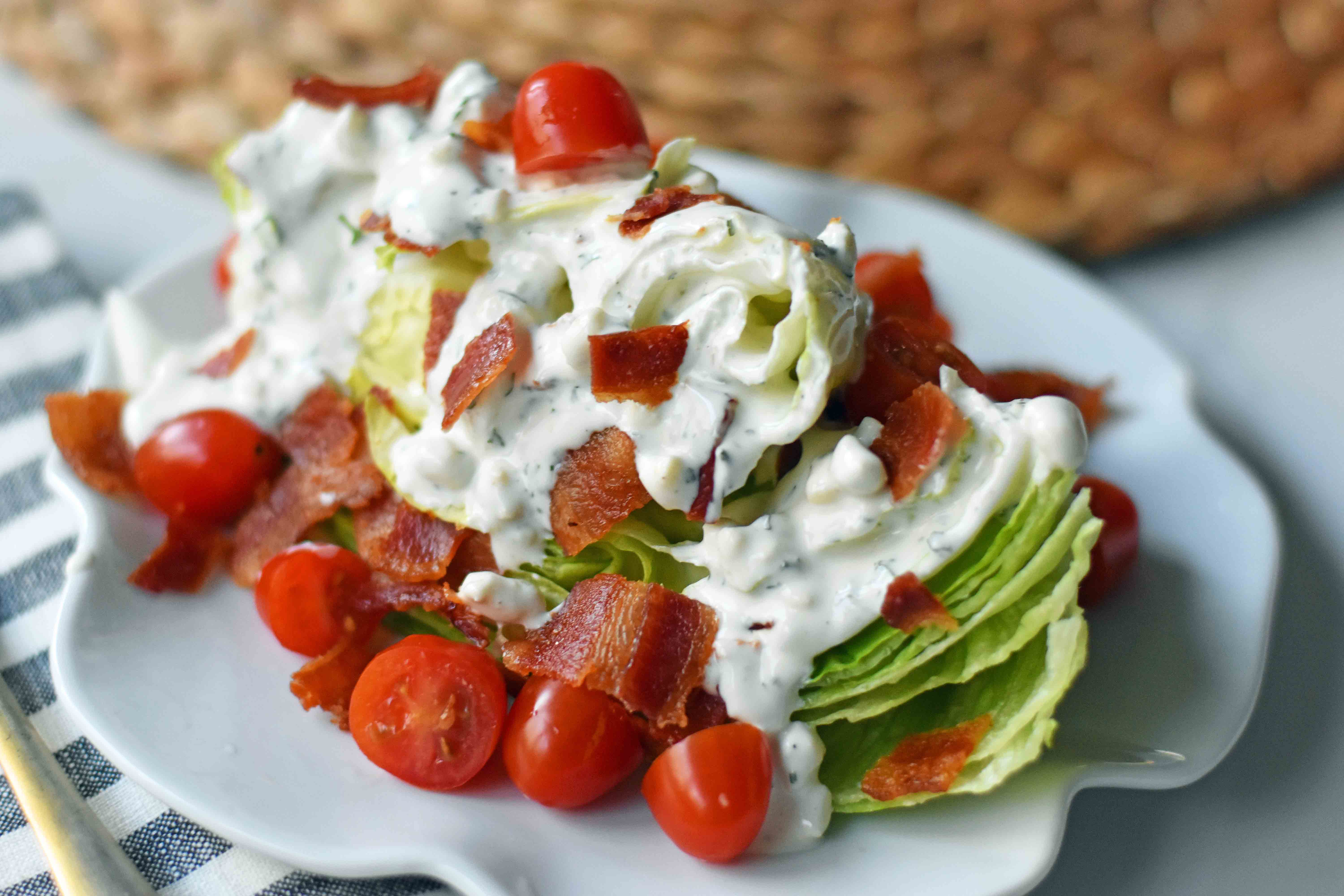 Ultimate Wedge Salad made with crisp iceberg lettuce, fresh cherry tomatoes, crispy bacon, with a homemade creamy ranch or blue cheese dressing. A classic, crowd-favorite salad. www.modernhoney.com