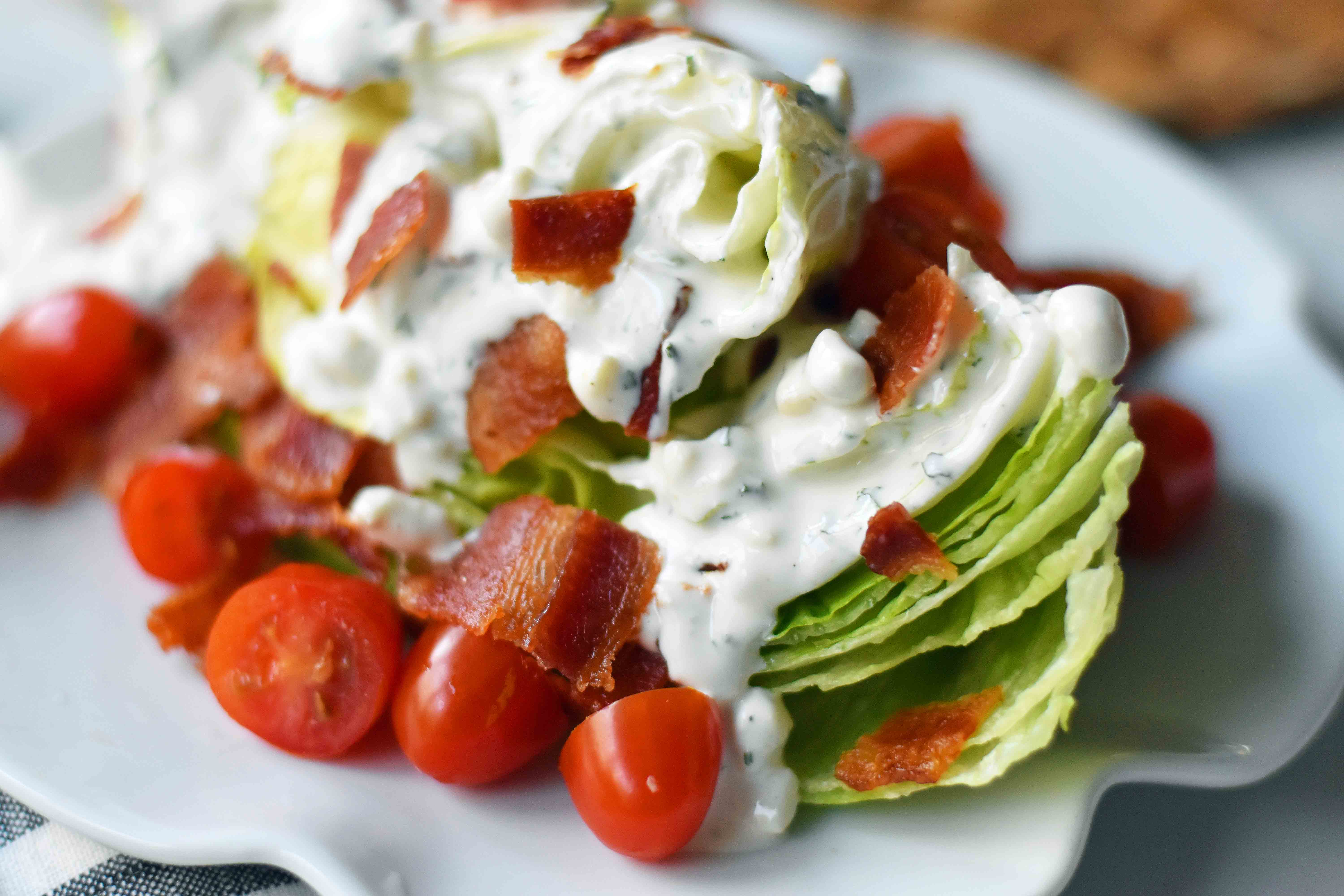 Ultimate Wedge Salad made with crisp iceberg lettuce, fresh cherry tomatoes, crispy bacon, with a homemade creamy ranch or blue cheese dressing. A classic, crowd-favorite salad. www.modernhoney.com