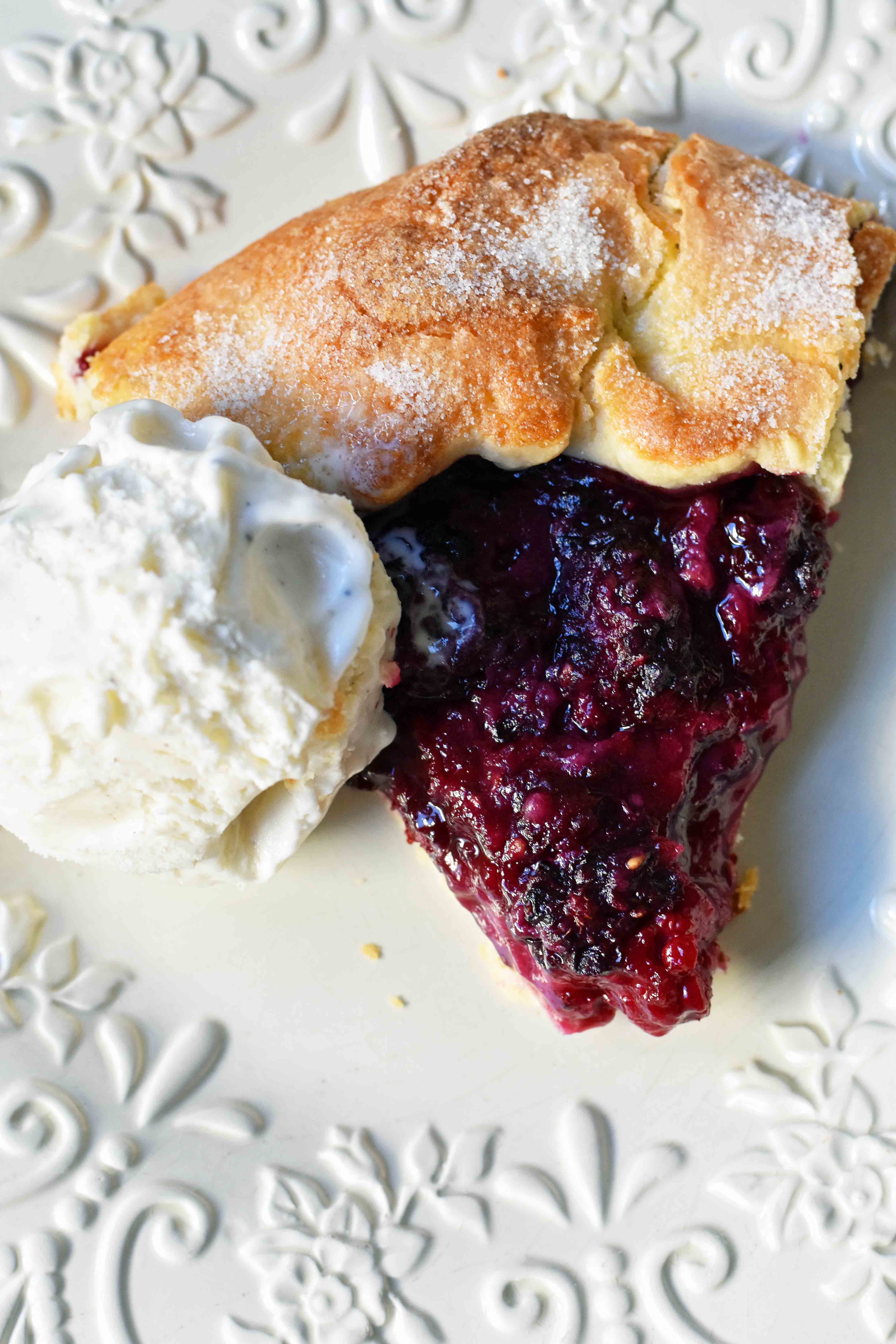 Blackberry Galette Crostata. An easy rustic summer dessert made with homemade buttery flaky pie crust with a sweet blackberry filling topped with vanilla bean ice cream. A much easier blackberry pie! www.modernhoney.com #galette #crostata #blackberrycrostata #blackberrygalette #summerdessert #berrydessert