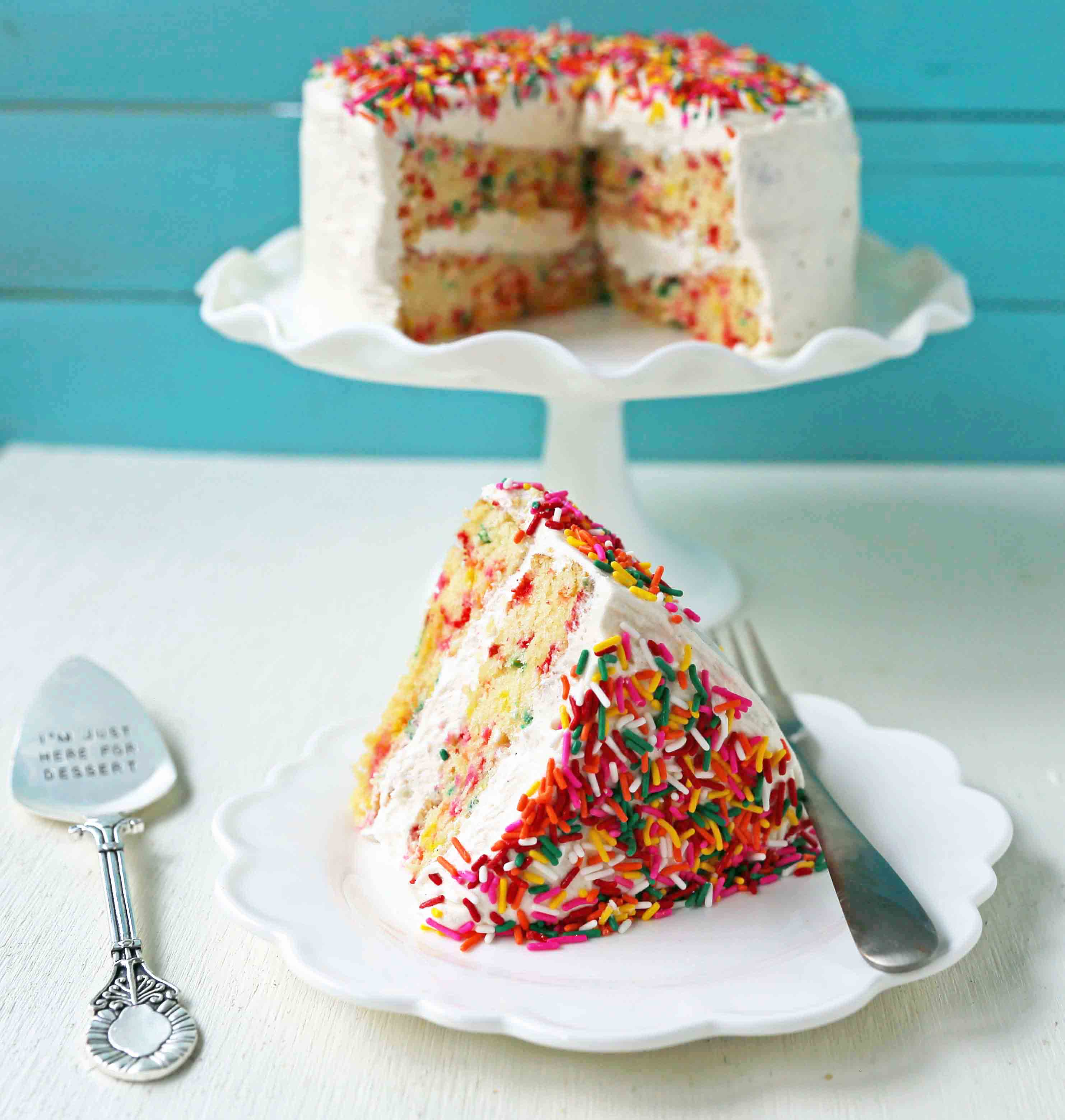 A fluffy homemade funfetti birthday cake with rainbow sprinkles topped with a light cream cheese buttercream frosting and an array of sprinkles. The perfect birthday cake! www.modernhoney.com #funfetti #funfetticake #sprinklescake #homemadefunfetticake #cake #homemadecake