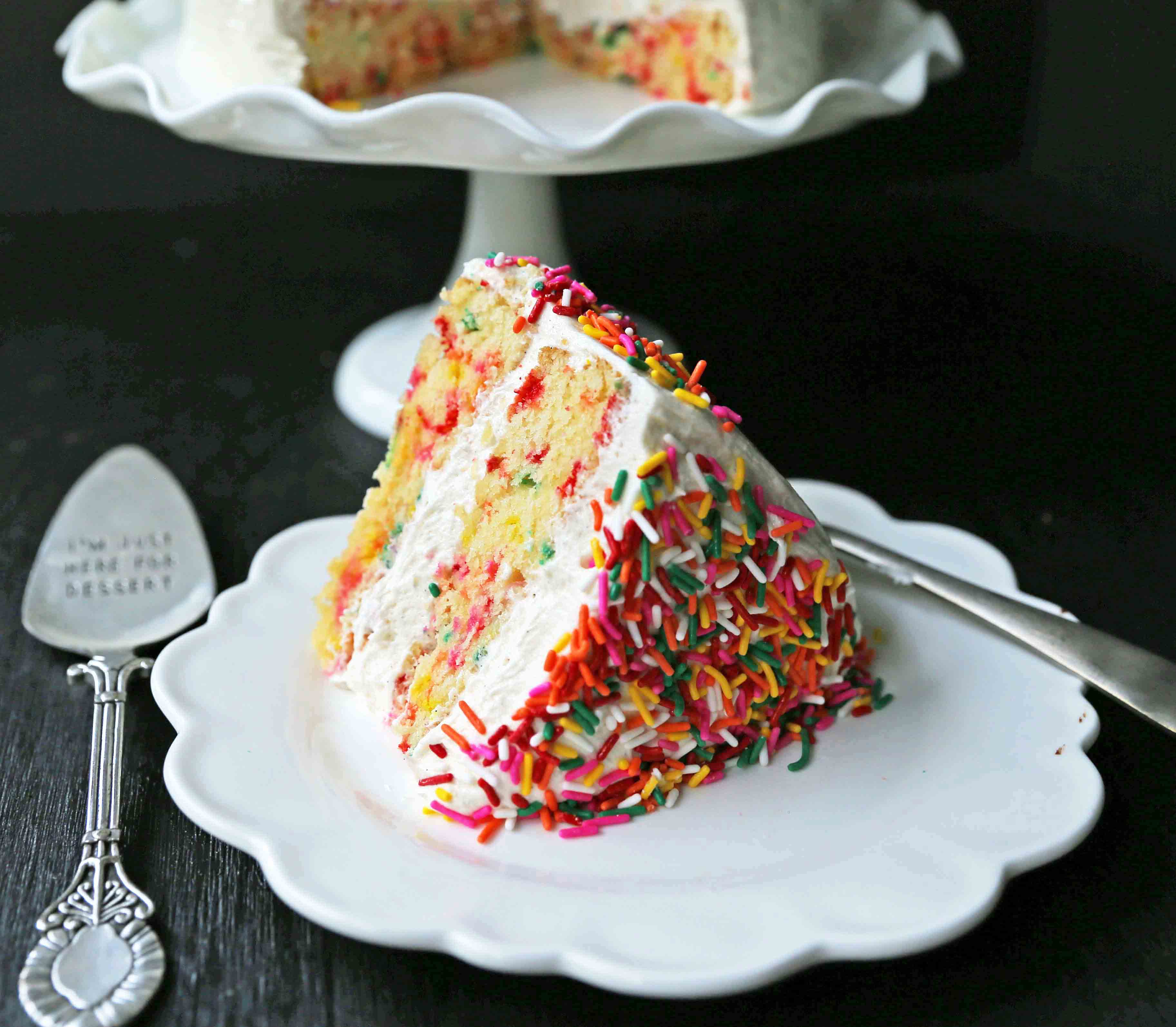 A fluffy homemade funfetti birthday cake with rainbow sprinkles topped with a light cream cheese buttercream frosting and an array of sprinkles. The perfect birthday cake! www.modernhoney.com #funfetti #funfetticake #sprinklescake #homemadefunfetticake #cake #homemadecake