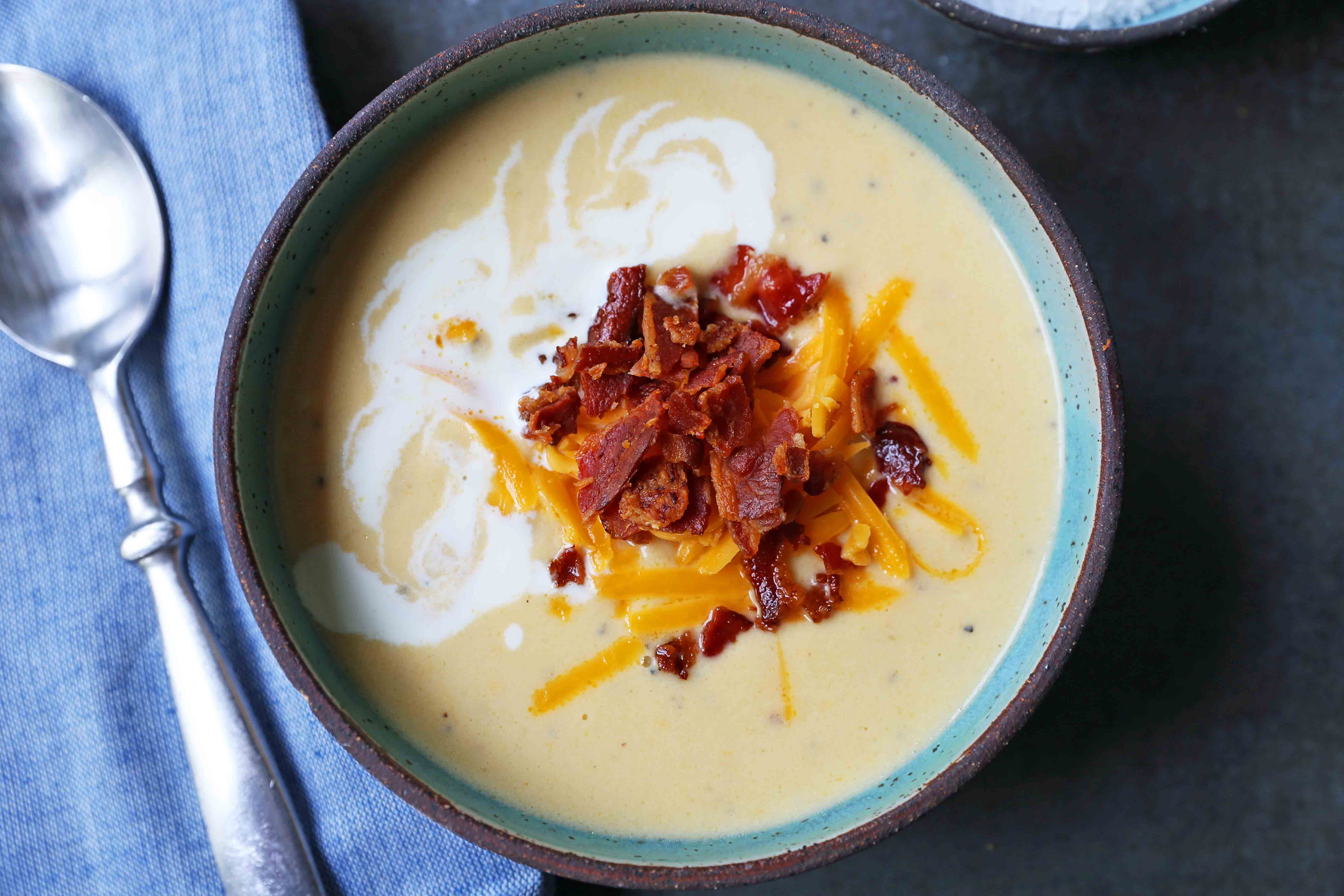 Cheesy Cauliflower Soup. A creamy cheesy cauliflower soup made with fresh cauliflower, cream, sharp cheddar cheese, and bacon. A velvety smooth cream of cauliflower soup will become a winter staple in your home! www.modernhoney.com #cauliflowersoup #cheesycauliflowersoup #creamofcauliflowersoup #soup #souprecipes
