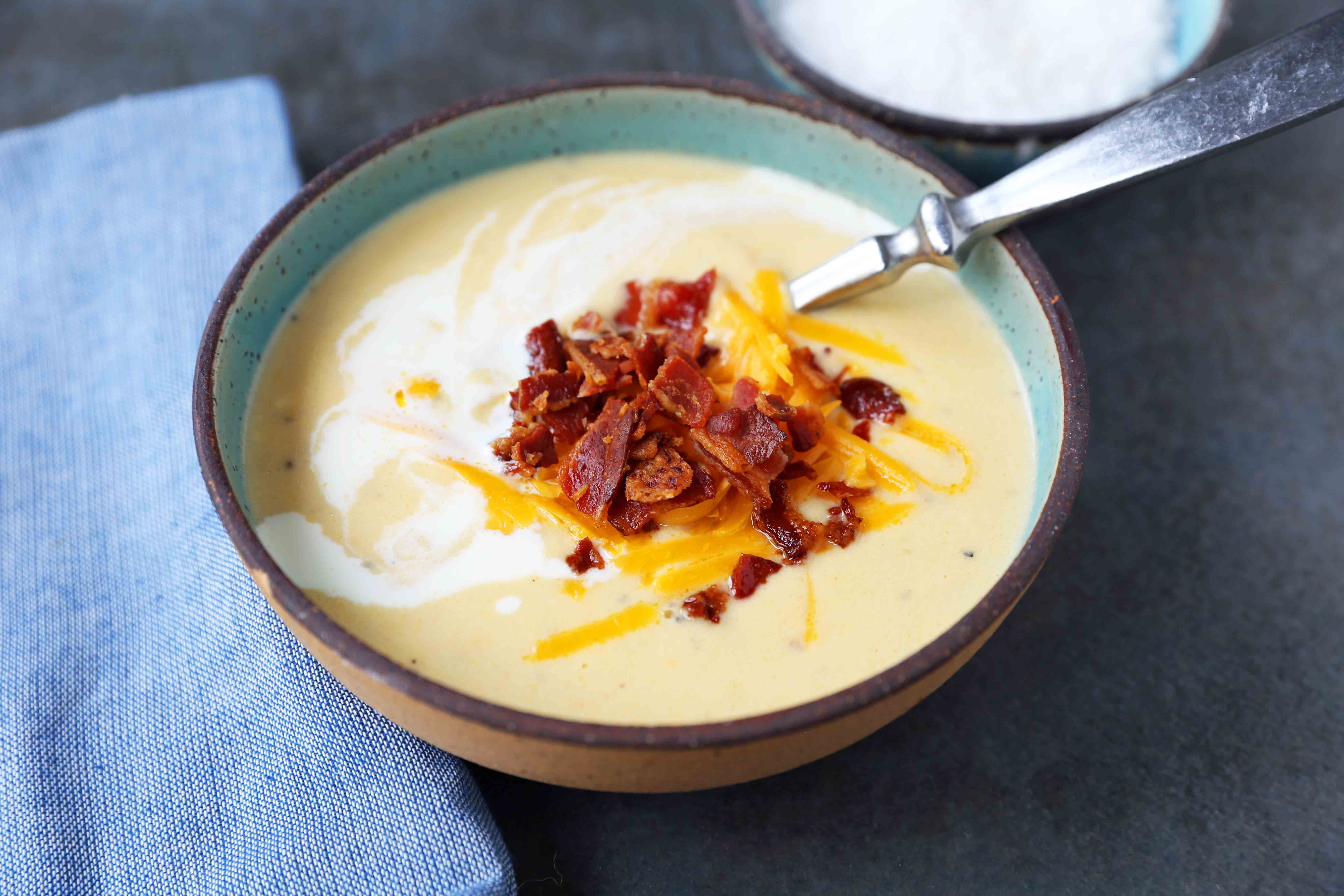 Cheesy Cauliflower Soup. A creamy cheesy cauliflower soup made with fresh cauliflower, cream, sharp cheddar cheese, and bacon. A velvety smooth cream of cauliflower soup will become a winter staple in your home! www.modernhoney.com #cauliflowersoup #cheesycauliflowersoup #creamofcauliflowersoup #soup #souprecipes