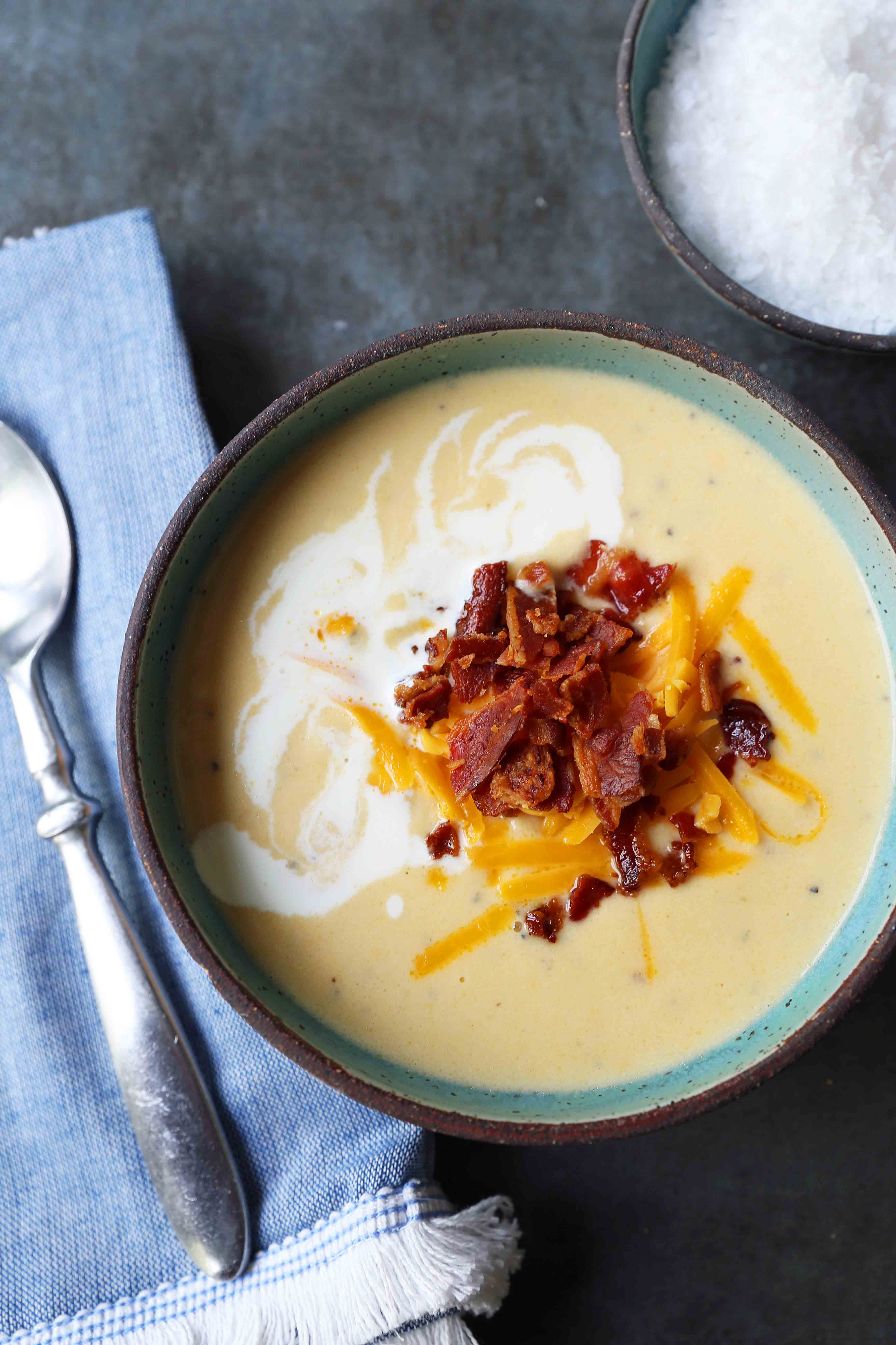 Cheesy Cauliflower Soup. A creamy cheesy cauliflower soup made with fresh cauliflower, cream, sharp cheddar cheese, and bacon. A velvety smooth cream of cauliflower soup will become a winter staple in your home! www.modernhoney.com #cauliflowersoup #cheesycauliflowersoup #creamofcauliflowersoup #soup #souprecipes