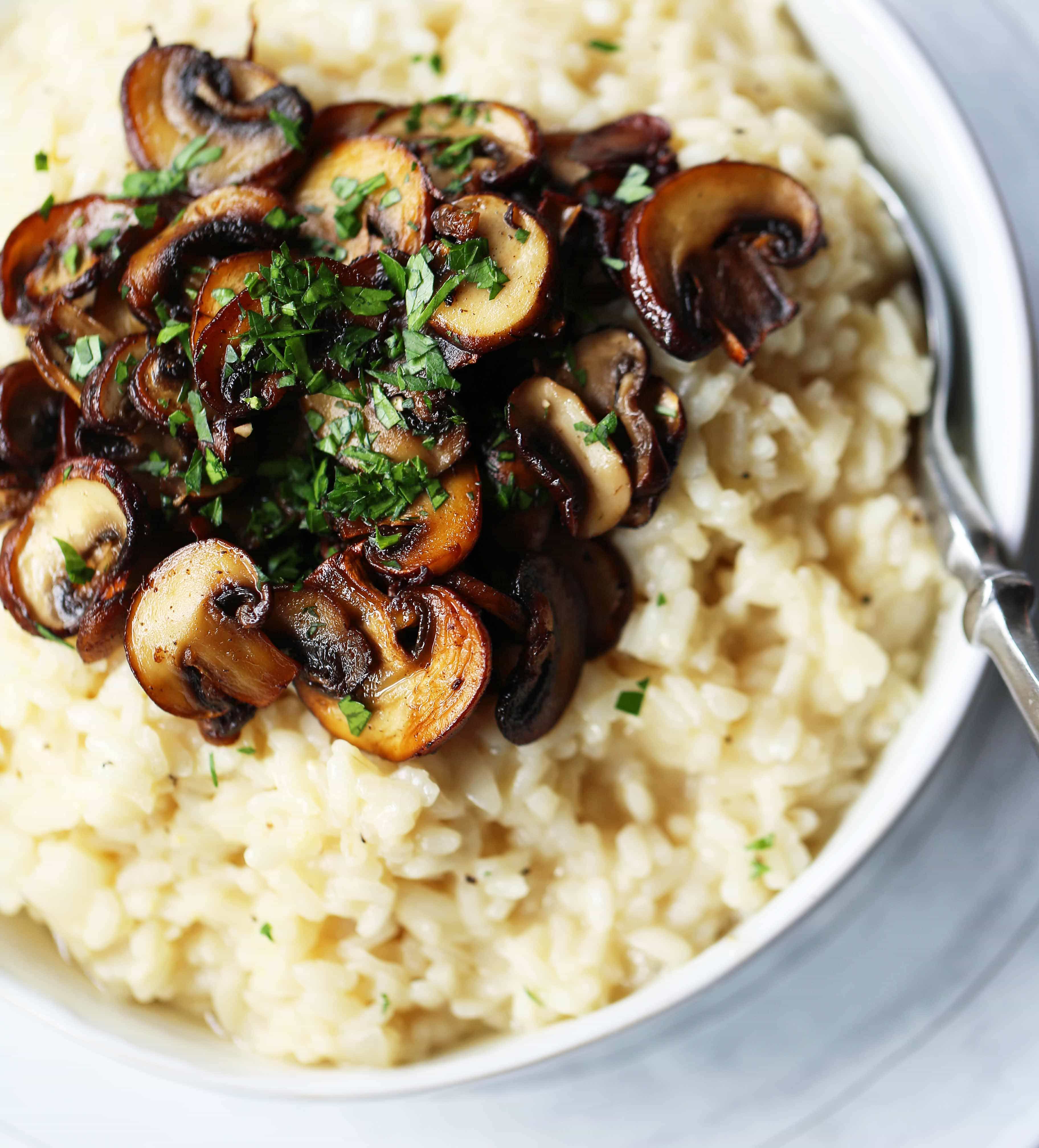 Creamy Mushroom Risotto. Rich, creamy rice slowly simmered with chicken broth, butter, parmesan cheese, and topped with butter sauteed mushrooms. www.modernhoney.com #risotto #homemaderisotto #mushroomrisotto