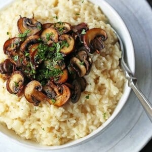 Creamy Mushroom Risotto. Rich, creamy rice slowly simmered with chicken broth, butter, parmesan cheese, and topped with butter sauteed mushrooms. www.modernhoney.com #risotto #homemaderisotto #mushroomrisotto