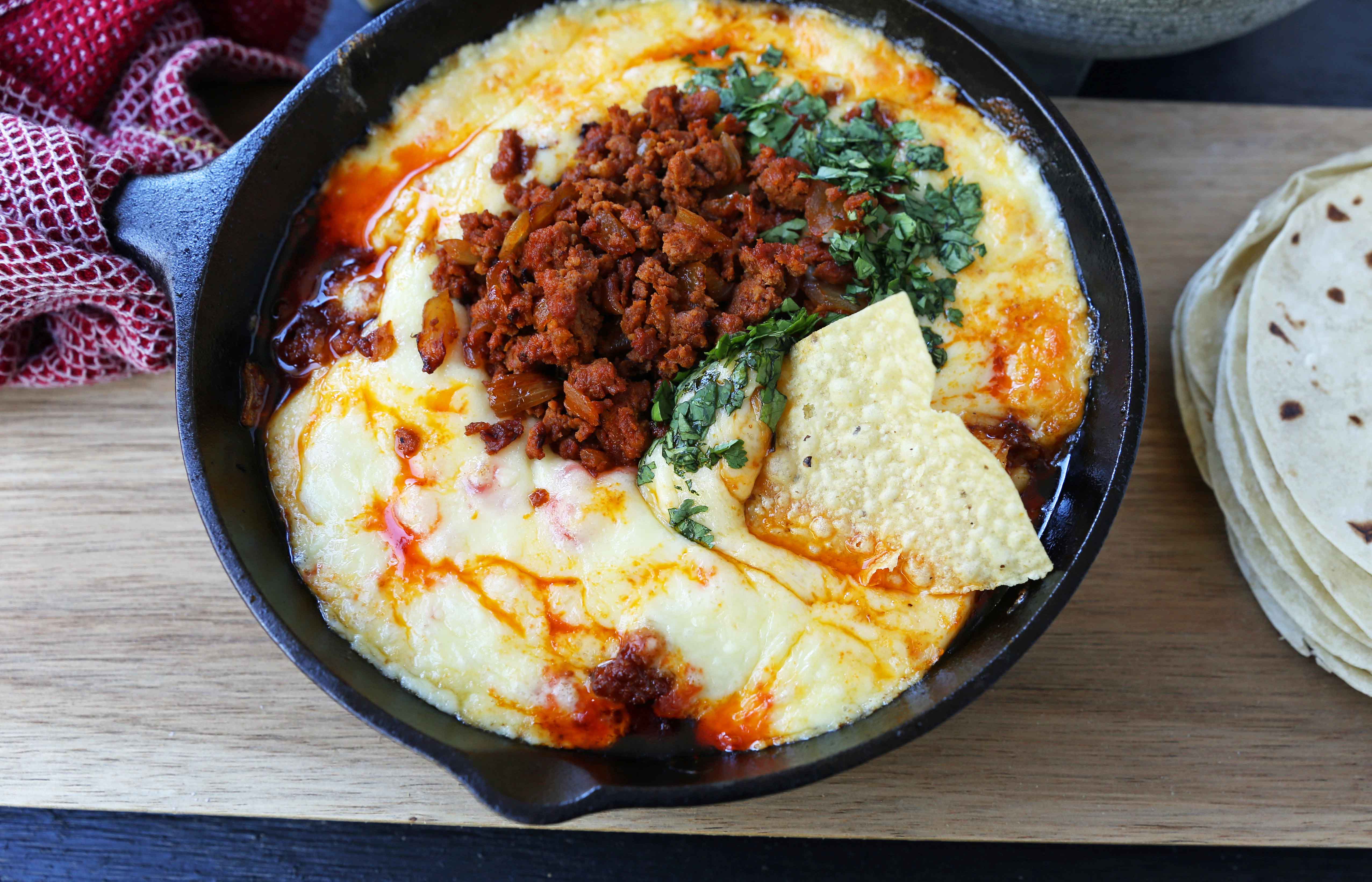 Queso Fundido with Chorizo. A skillet of melted Mexican cheeses seasoned with peppers, onions, and spicy Mexican chorizo sausage and served with hot tortillas or chips. The perfect Mexican appetizer! www.modernhoney.com #appetizer #appetizers #mexican #mexicanfood #queso #quesofundido