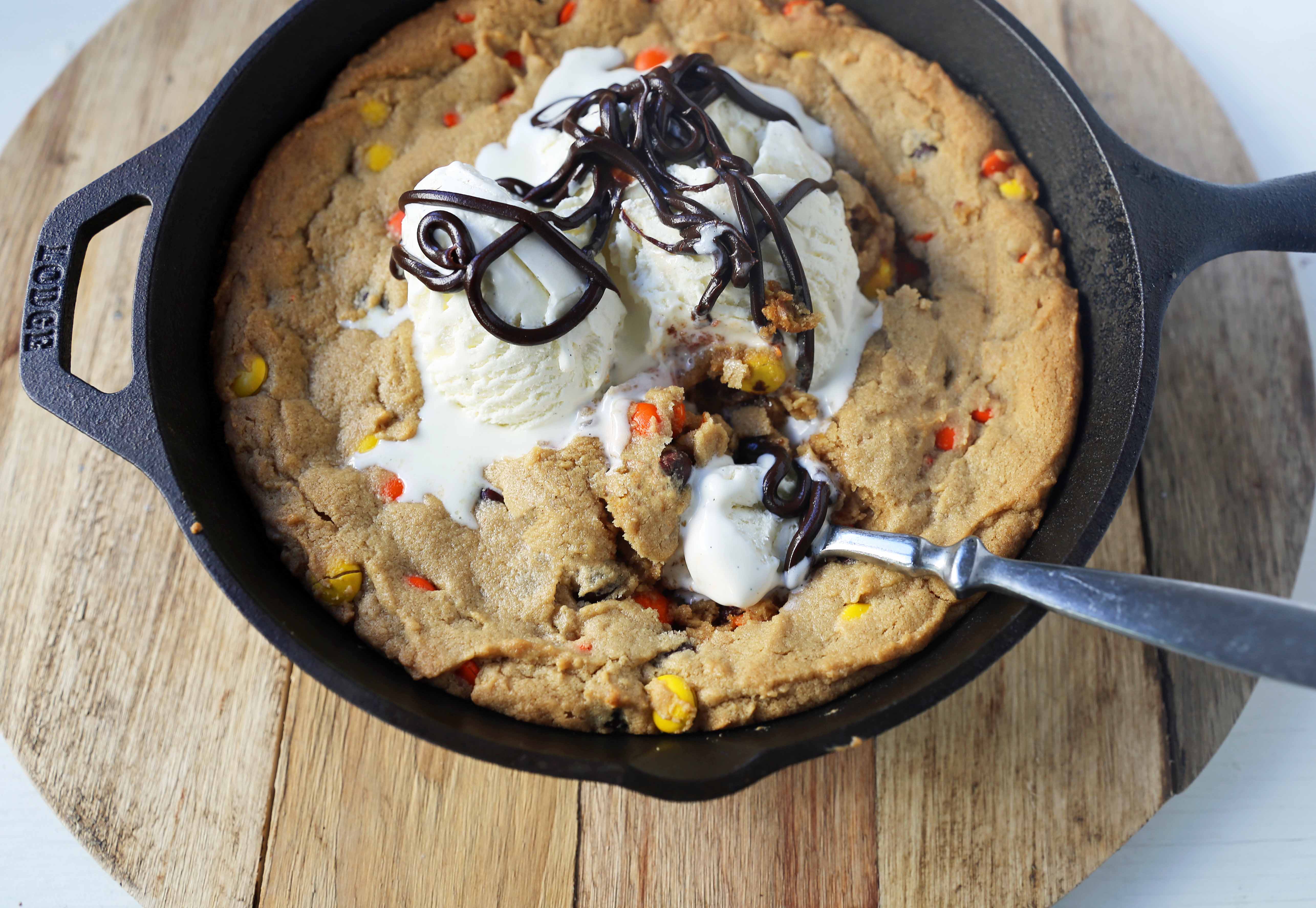 Peanut Butter Skillet Cookie. Homemade peanut butter cookie dough with Reeses Pieces baked until ooey gooey and topped with vanilla ice cream and hot fudge. www.modernhoney.com #peanutbutter #peanutbuttercookies #peanutbutterpizookie #pizookie