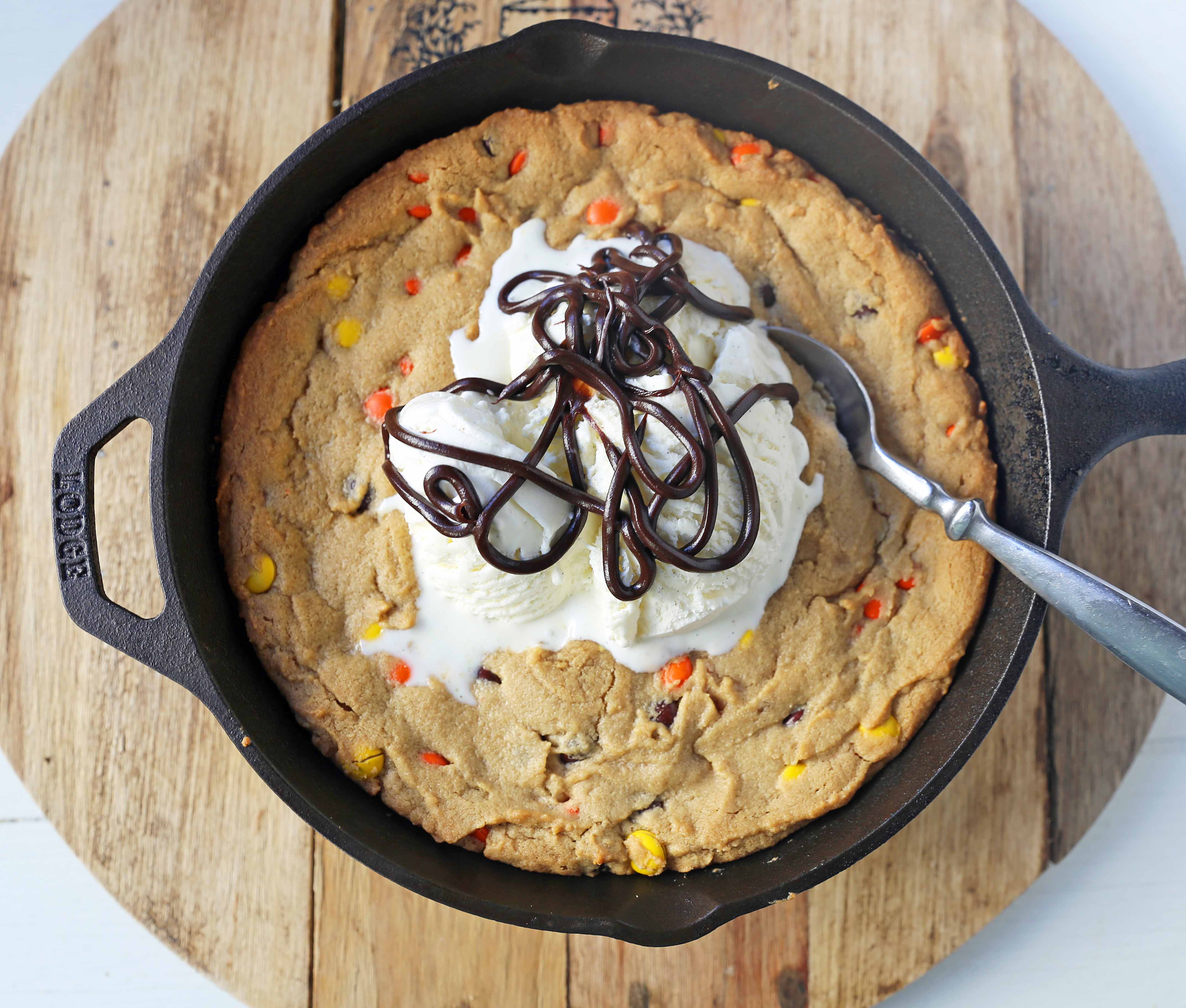 Peanut Butter Skillet Cookie. Homemade peanut butter cookie dough with Reeses Pieces baked until ooey gooey and topped with vanilla ice cream and hot fudge. www.modernhoney.com #peanutbutter #peanutbuttercookies #peanutbutterpizookie #pizookie