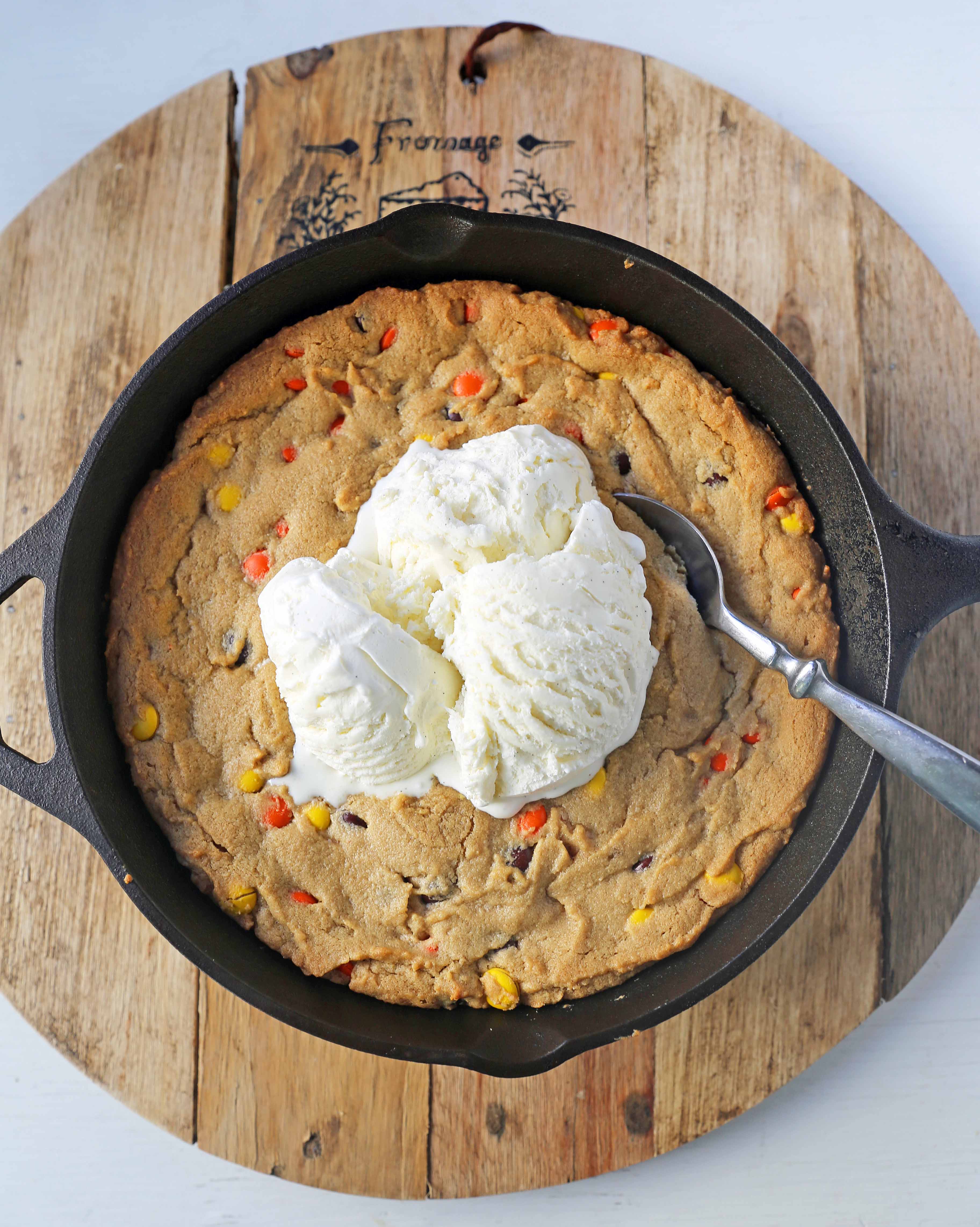 Peanut Butter Skillet Cookie. Homemade peanut butter cookie dough with Reeses Pieces baked until ooey gooey and topped with vanilla ice cream and hot fudge. www.modernhoney.com #peanutbutter #peanutbuttercookies #peanutbutterpizookie #pizookie