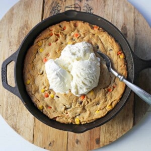 Peanut Butter Skillet Cookie. Homemade peanut butter cookie dough with Reeses Pieces baked until ooey gooey and topped with vanilla ice cream and hot fudge. www.modernhoney.com #peanutbutter #peanutbuttercookies #peanutbutterpizookie #pizookie