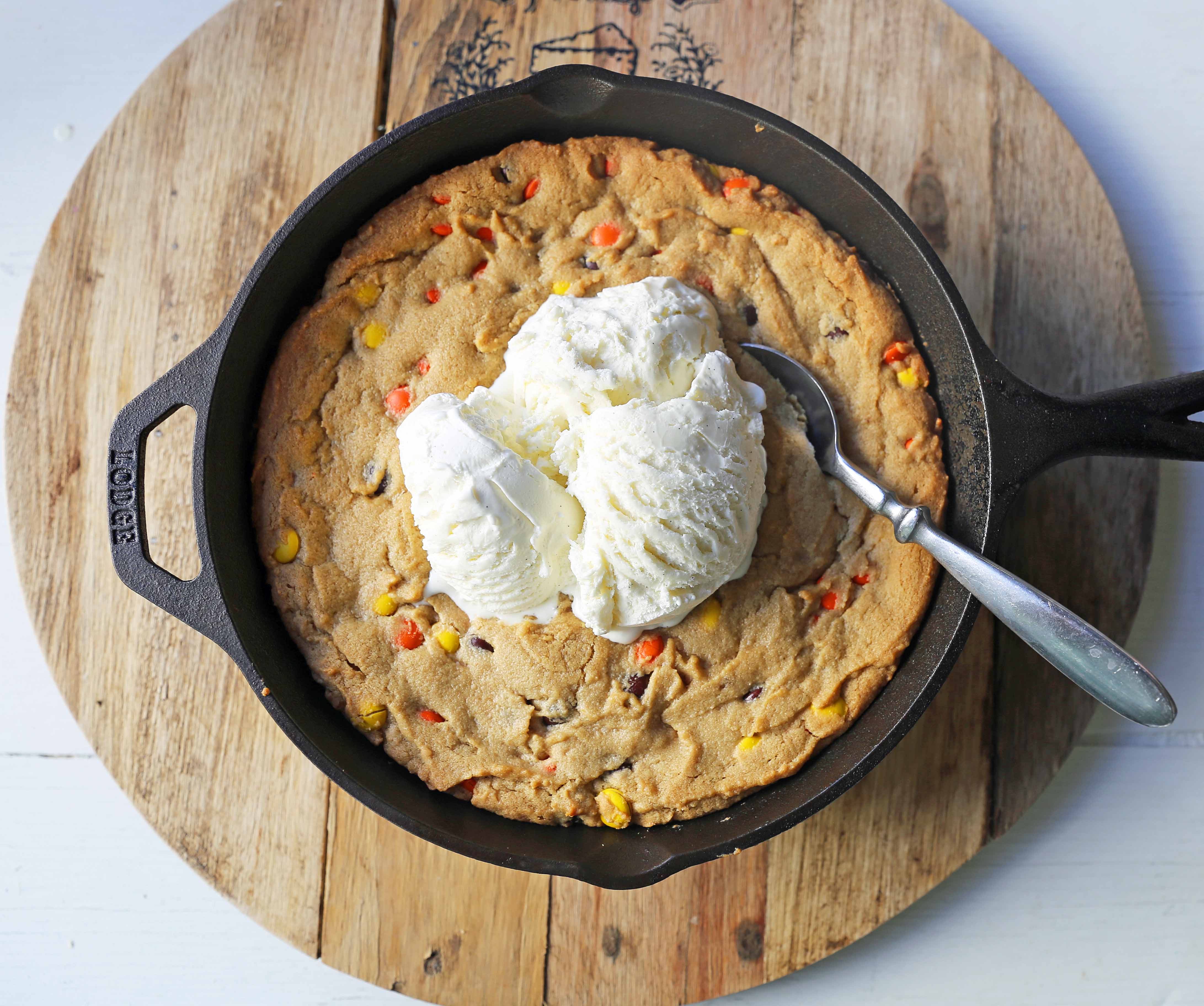 Peanut Butter Skillet Cookie. Homemade peanut butter cookie dough with Reeses Pieces baked until ooey gooey and topped with vanilla ice cream and hot fudge. www.modernhoney.com #peanutbutter #peanutbuttercookies #peanutbutterpizookie #pizookie 