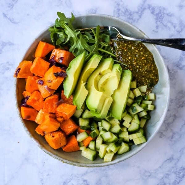 Buddha Bowl with Pistachio Pesto A healthy vegan bowl made with roasted sweet potatoes, onions, fresh avocado, cucumbers, arugula, quinoa, and homemade pistachio pesto. www.modernhoney.com #buddhabowl #vegan #vegetarian #flowerchild