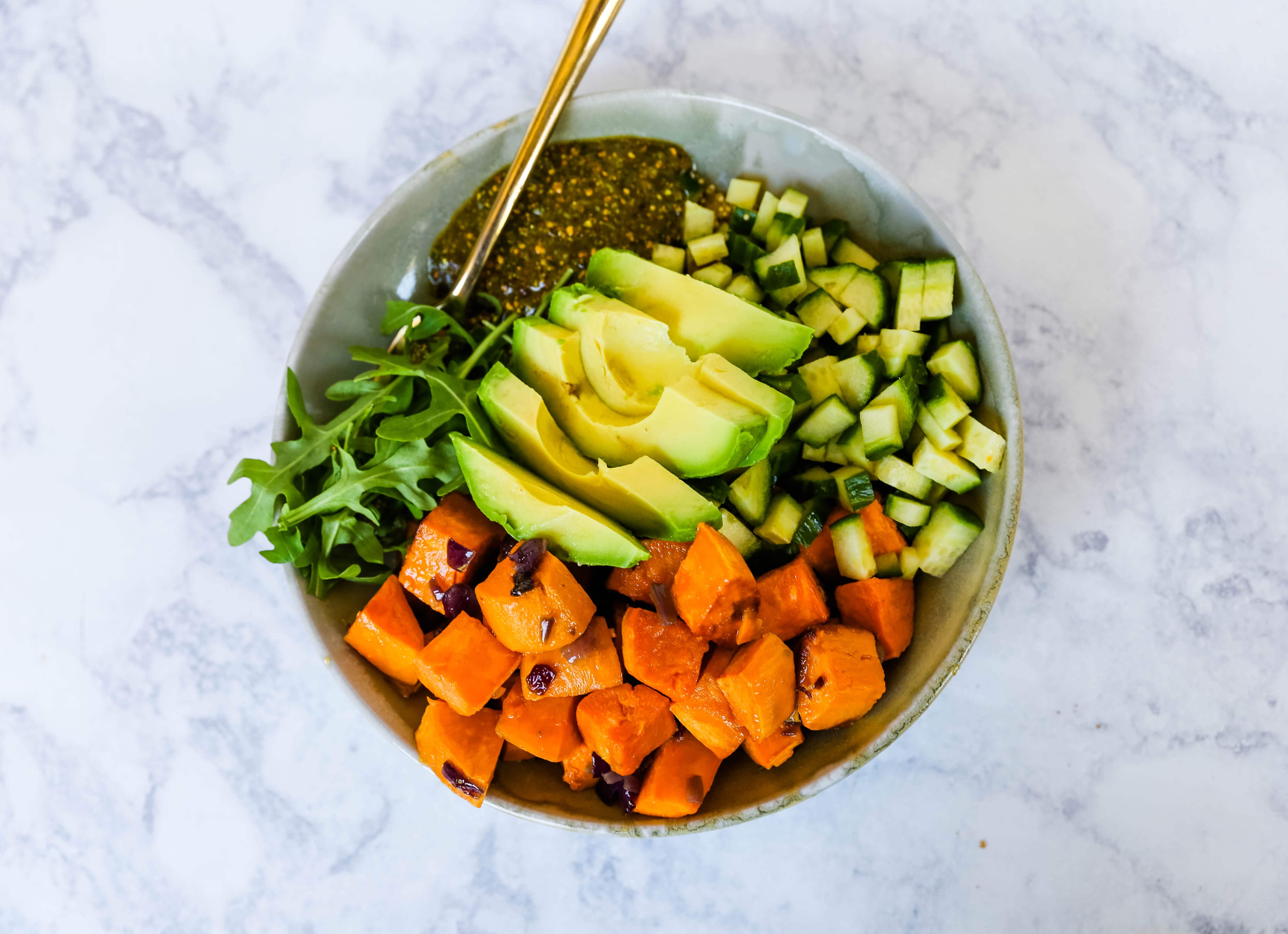 Buddha Bowl with Pistachio Pesto A healthy vegan bowl made with roasted sweet potatoes, onions, fresh avocado, cucumbers, arugula, quinoa, and homemade pistachio pesto. www.modernhoney.com #buddhabowl #vegan #vegetarian #flowerchild 