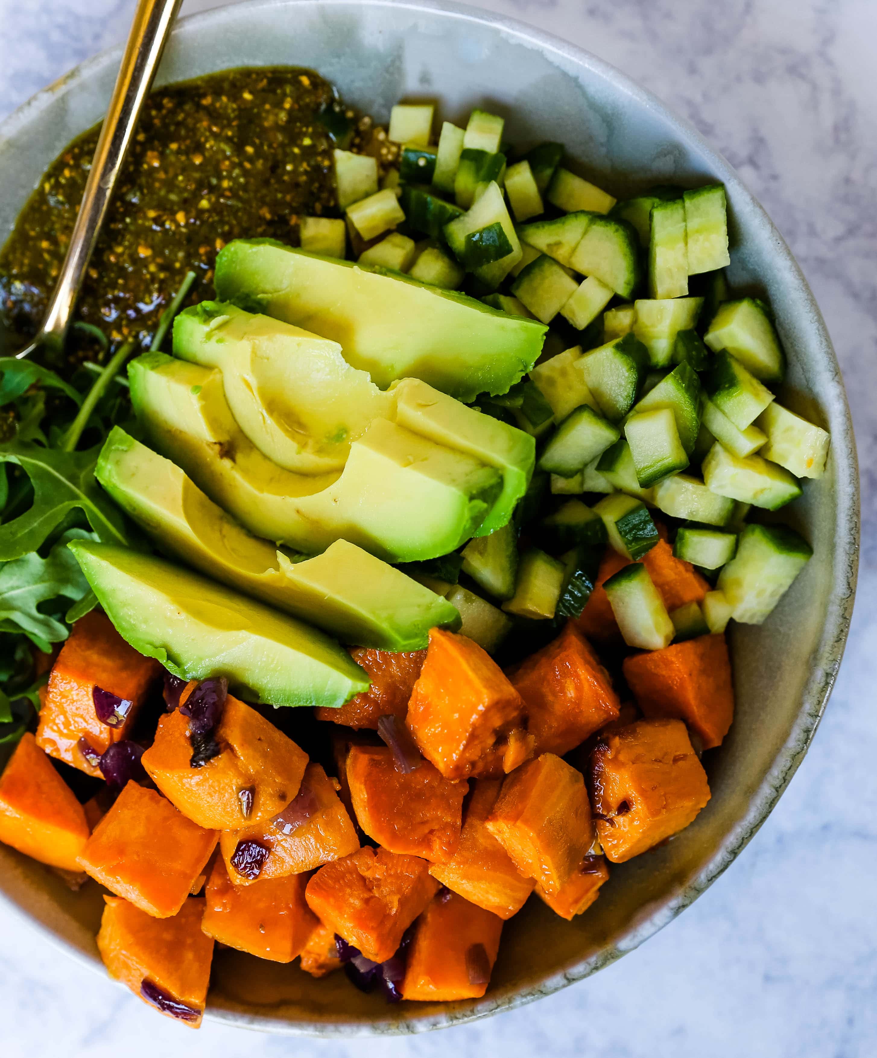 Buddha Bowl with Pistachio Pesto A healthy vegan bowl made with roasted sweet potatoes, onions, fresh avocado, cucumbers, arugula, quinoa, and homemade pistachio pesto. www.modernhoney.com #buddhabowl #vegan #vegetarian #flowerchild 