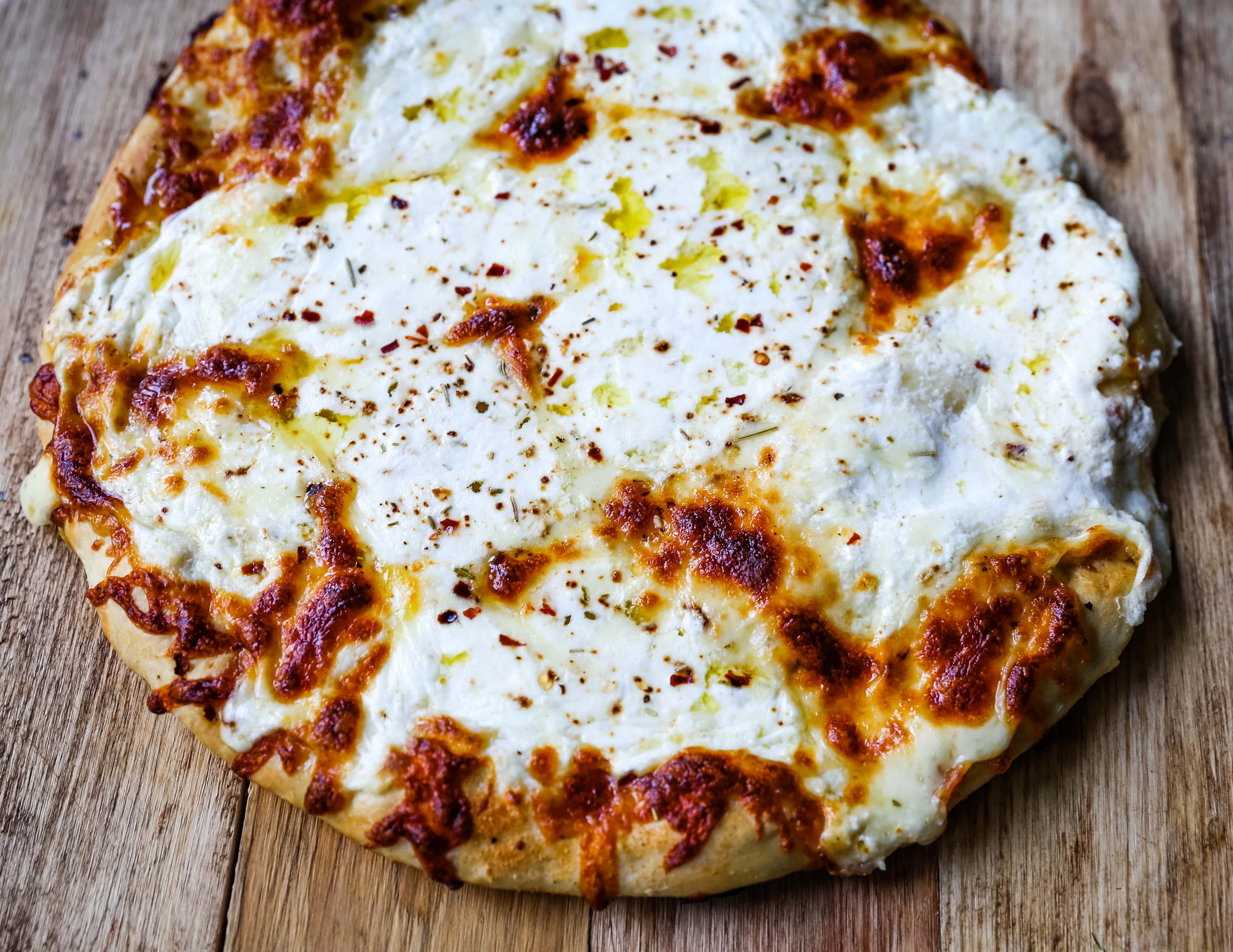 The Best 3-Cheese White Pizza A New-York Style white pizza with drizzled olive oil, mozzarella, parmesan, and ricotta cheese with Italian herbs. www.modernhoney.com #pizzabianca #whitepizza #pizza 