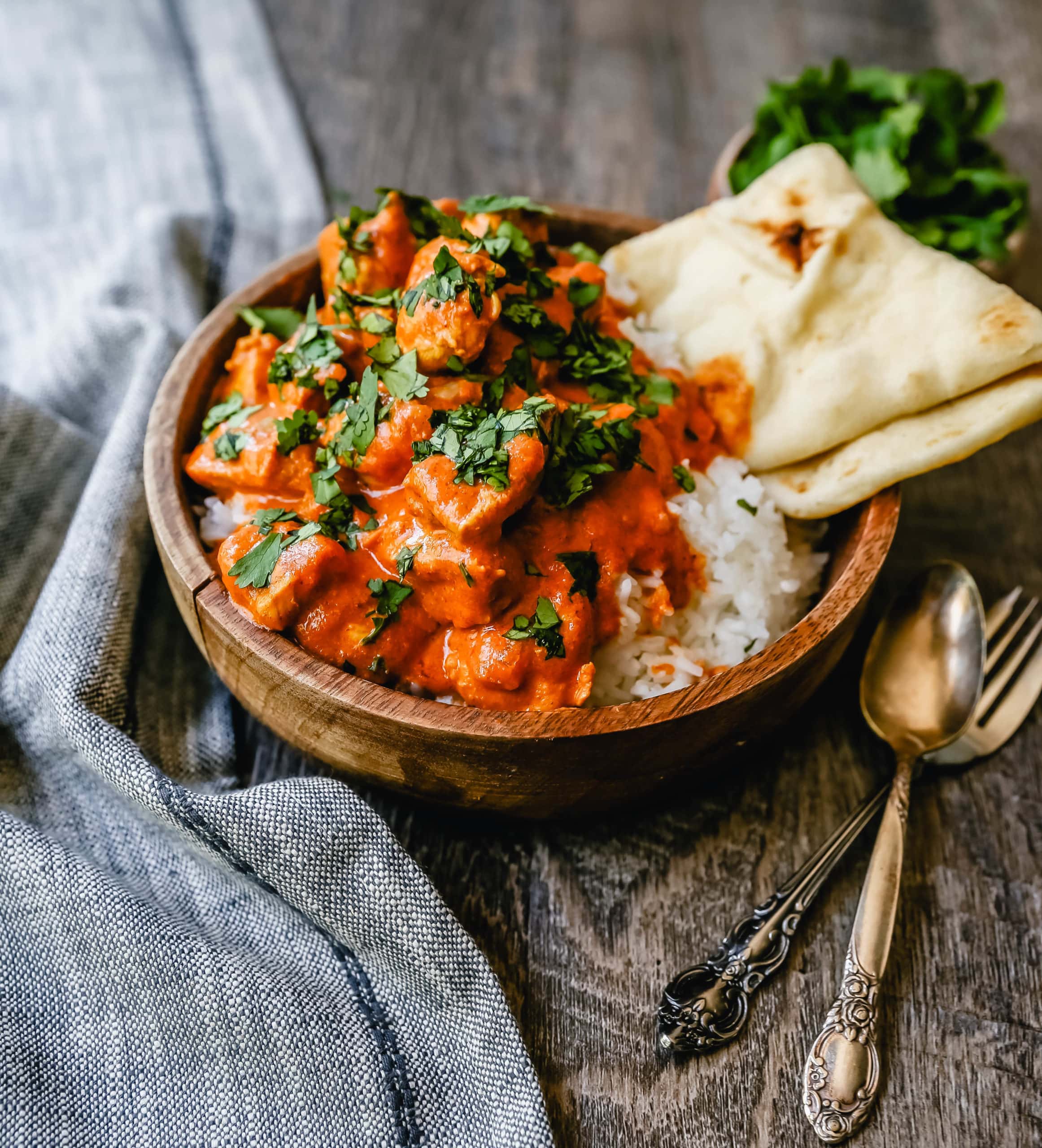 What is Butter Chicken? A popular Indian dish made with chicken marinated in yogurt and spices. It is sautéed and then simmered in an Indian spiced tomato cream sauce. The tomato cream sauce is made by sautéing butter and onions together and adding in tomato puree, Indian spices, and cream.  It is velvety smooth and full of rich robust flavor. Butter Chicken can be served over rice or with a side of Naan bread. We are obsessed with naan bread in our home and have it stockpiled in our freezer at all times. I love to heat it up in a skillet with a touch of butter and dip it into the butter chicken. 