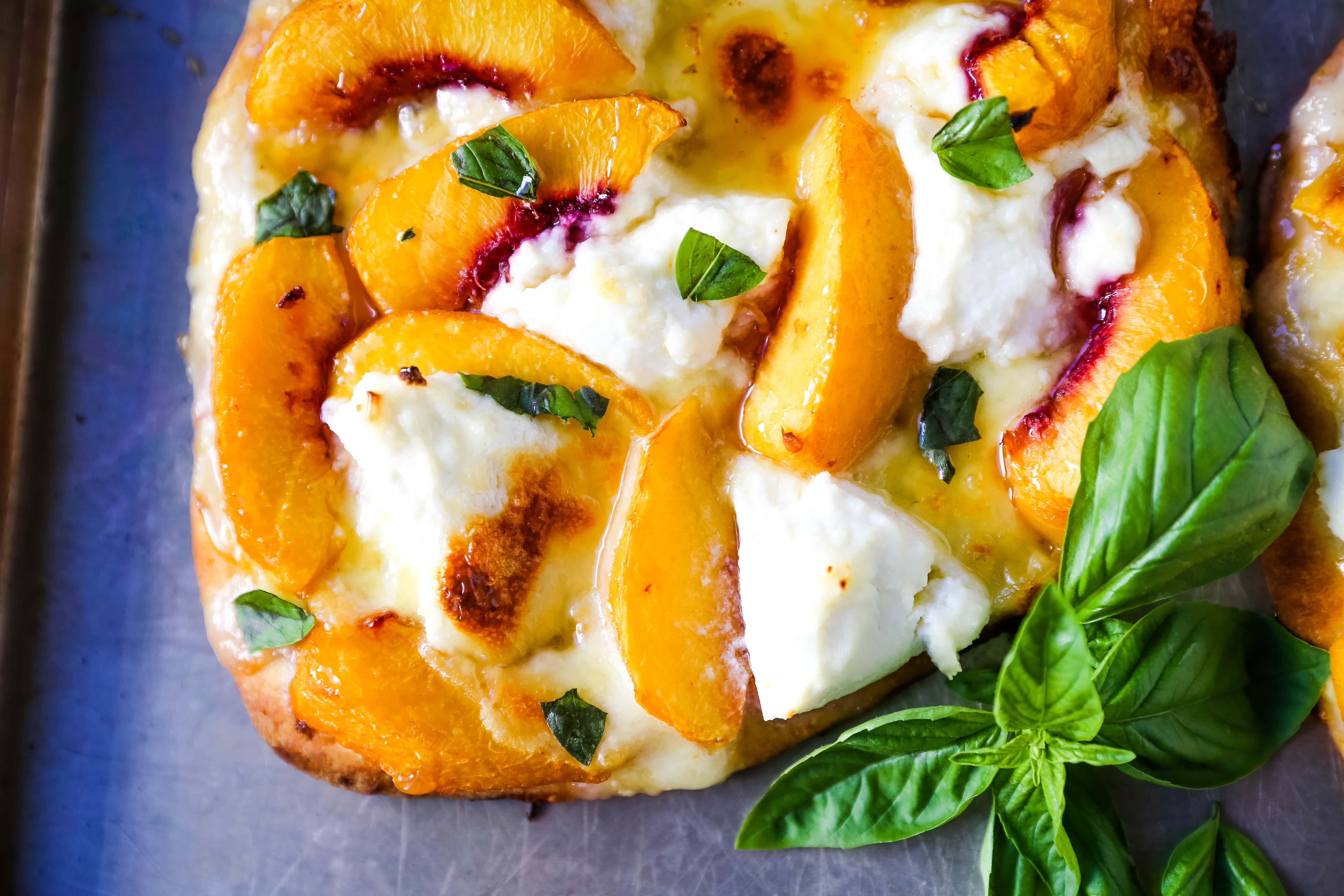 Peach Basil Mozzarella Flatbread Fresh peaches, basil ribbons, ricotta cheese, a drizzle of honey, fresh mozzarella all on a buttery flatbread. The perfect summer pizza!  www.modernhoney.com #peachpizza #flatbread #peachflatbread #summerpizza #peachrecipes