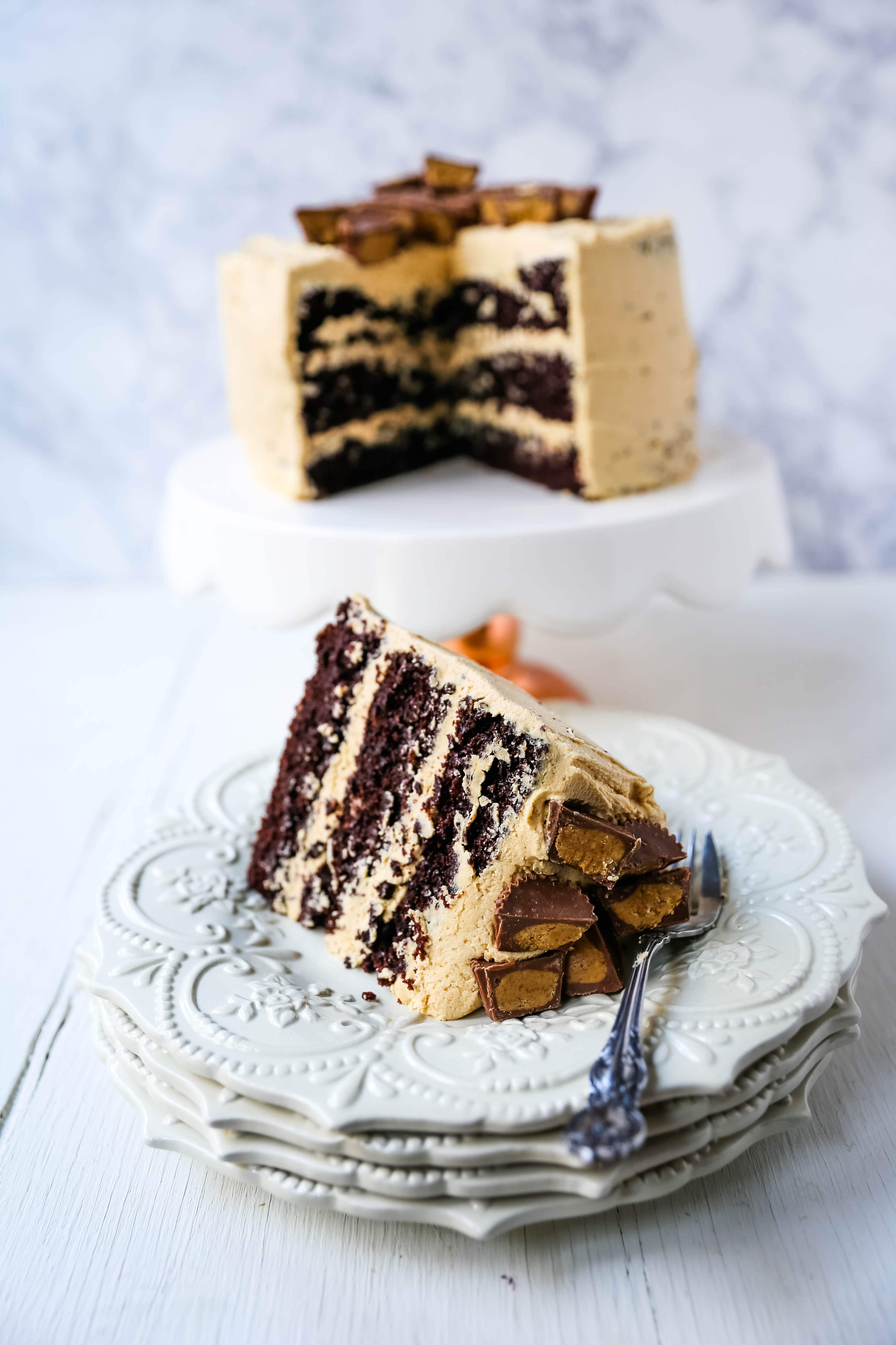 Chocolate Cake with Peanut Butter Frosting A moist 5-Star Rated Chocolate Cake with Creamy Peanut Butter Frosting topped with Peanut Butter Cups. www.modernhoney.com #peanutbutter #chocolatepeanutbuttercake #chocolatecake