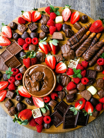 Chocolate Dessert Board A decadent chocolate board with an assortment of chocolate truffles, milk chocolate, dark chocolate hearts, chocolate covered pretzels, Nutella, berries, and more! www.modernhoney.com #chocolate #valentinesday #chocolateboard #dessert #desserts #chocolatedessert