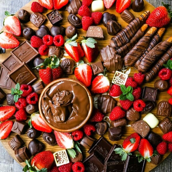 Chocolate Dessert Board A decadent chocolate board with an assortment of chocolate truffles, milk chocolate, dark chocolate hearts, chocolate covered pretzels, Nutella, berries, and more! www.modernhoney.com #chocolate #valentinesday #chocolateboard #dessert #desserts #chocolatedessert