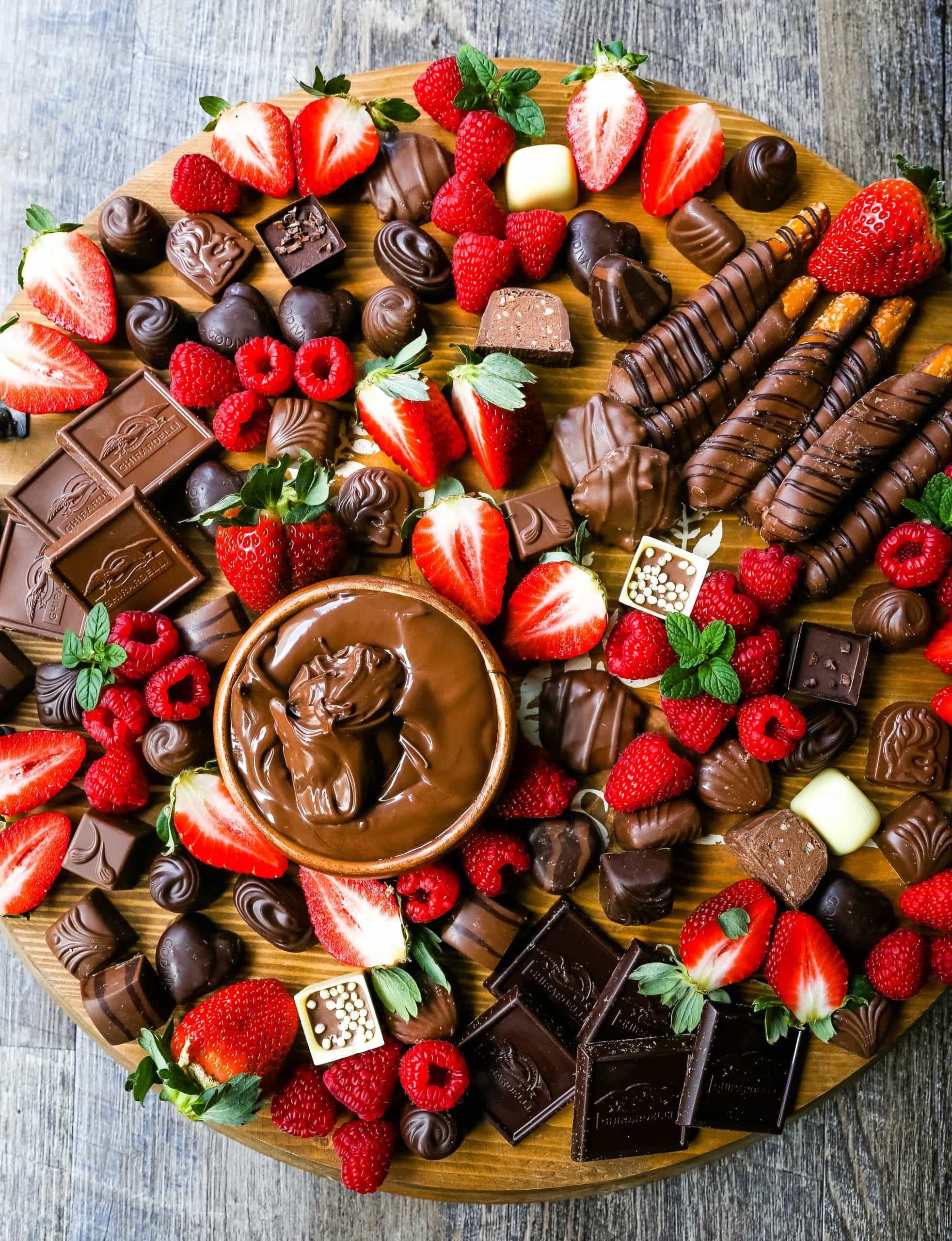 Chocolate Dessert Board A decadent chocolate board with an assortment of chocolate truffles, milk chocolate, dark chocolate hearts, chocolate covered pretzels, Nutella, berries, and more! www.modernhoney.com #chocolate #valentinesday #chocolateboard #dessert #desserts #chocolatedessert