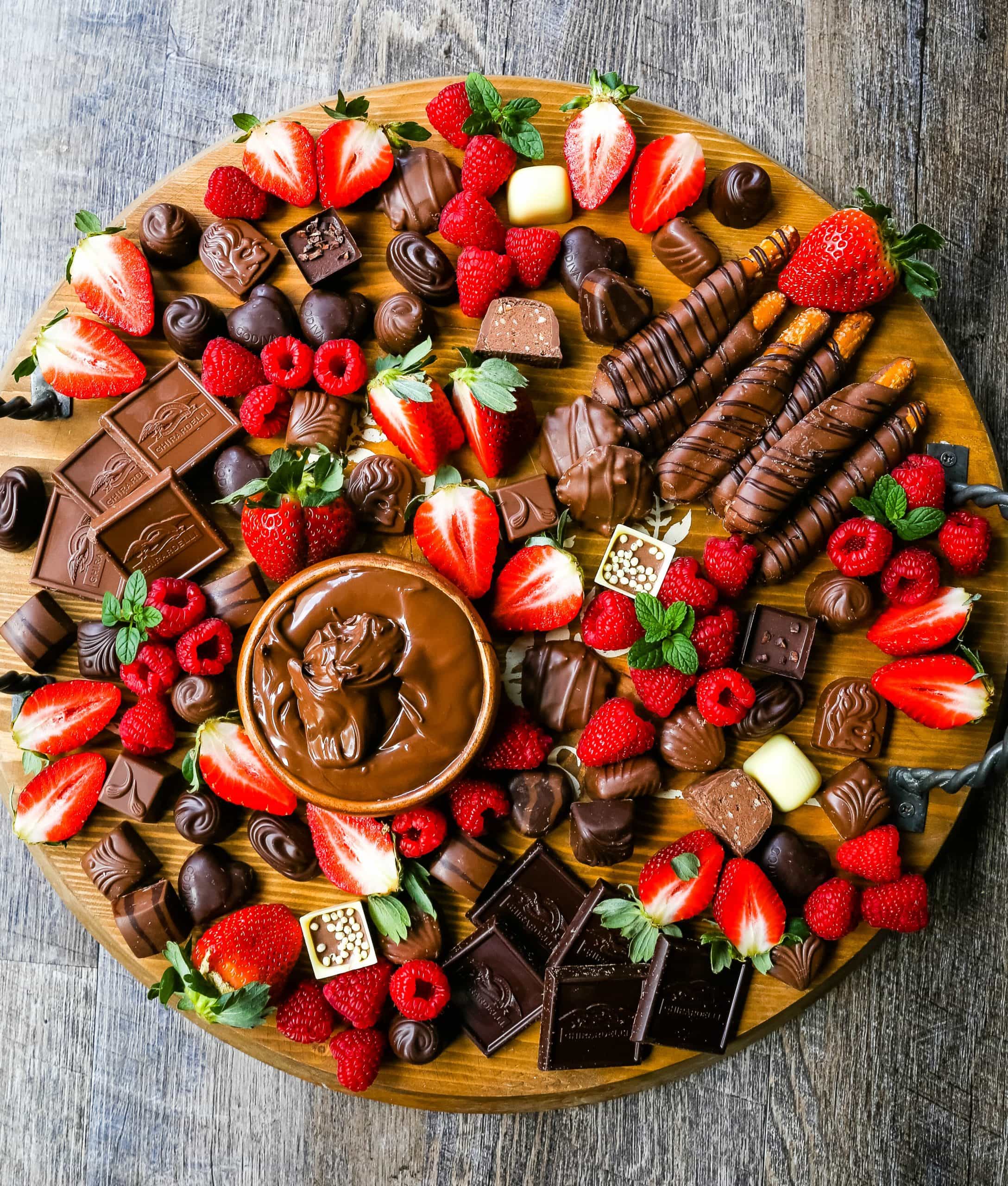 Chocolate Dessert Board A decadent chocolate board with an assortment of chocolate truffles, milk chocolate, dark chocolate hearts, chocolate covered pretzels, Nutella, berries, and more! www.modernhoney.com #chocolate #valentinesday #chocolateboard #dessert #desserts #chocolatedessert