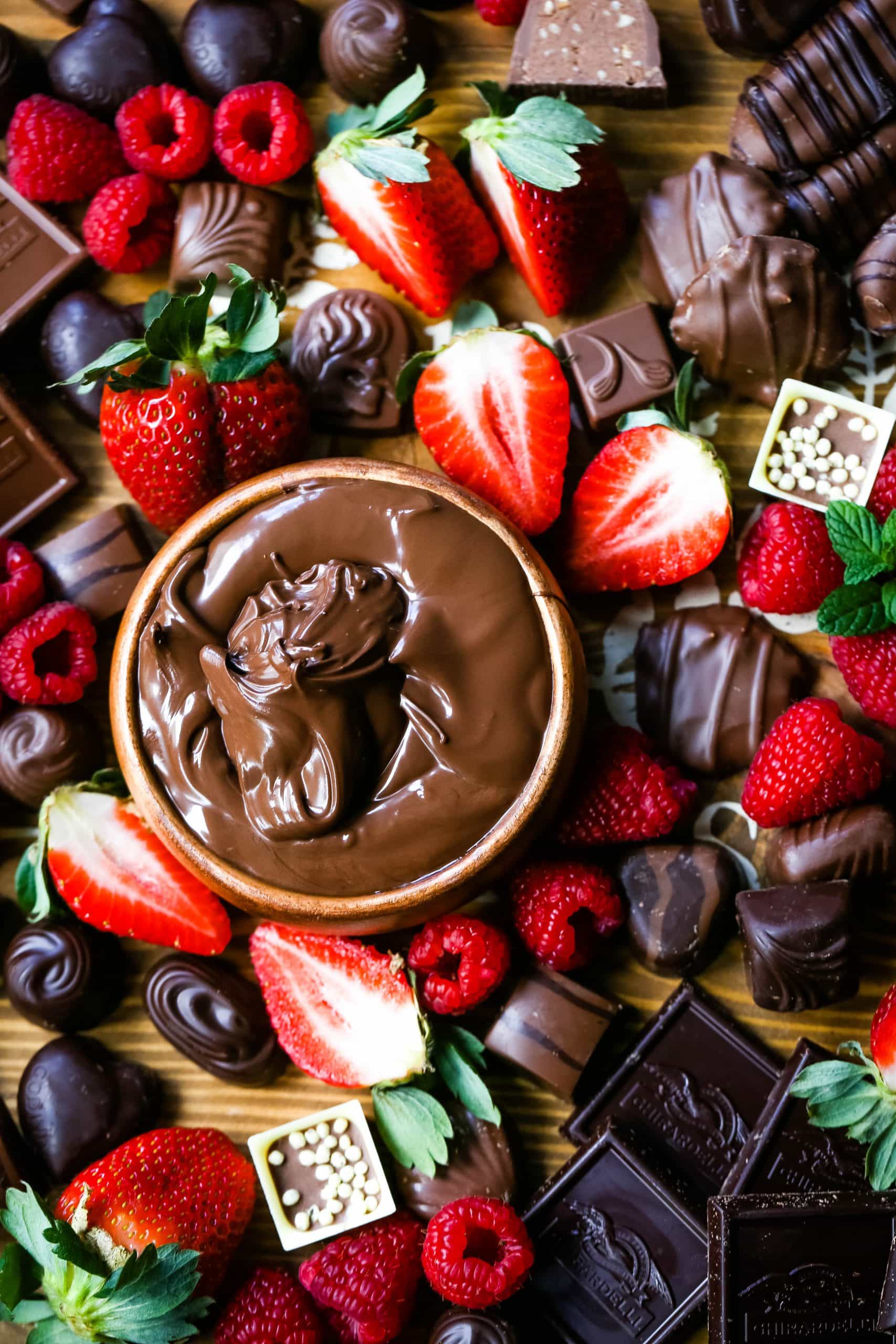 Chocolate Dessert Board A decadent chocolate board with an assortment of chocolate truffles, milk chocolate, dark chocolate hearts, chocolate covered pretzels, Nutella, berries, and more! www.modernhoney.com #chocolate #valentinesday #chocolateboard #dessert #desserts #chocolatedessert