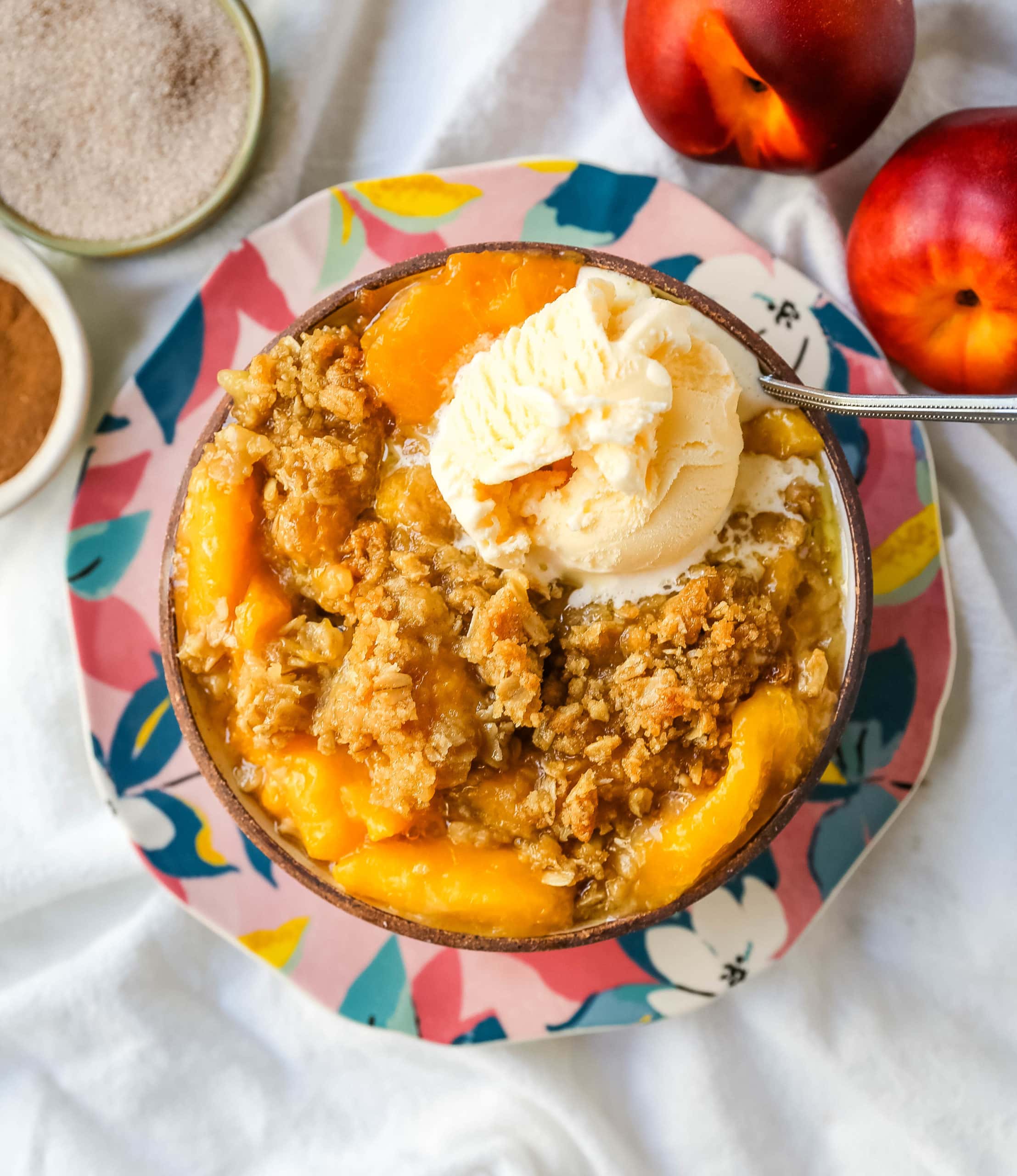 Peach Crisp. Fresh sweetened peaches with a brown sugar oat crumble topping with creamy vanilla ice cream. The perfect summer dessert! www.modernhoney.com #peach #peaches #peachcrisp #peachrecipes #peachdessert